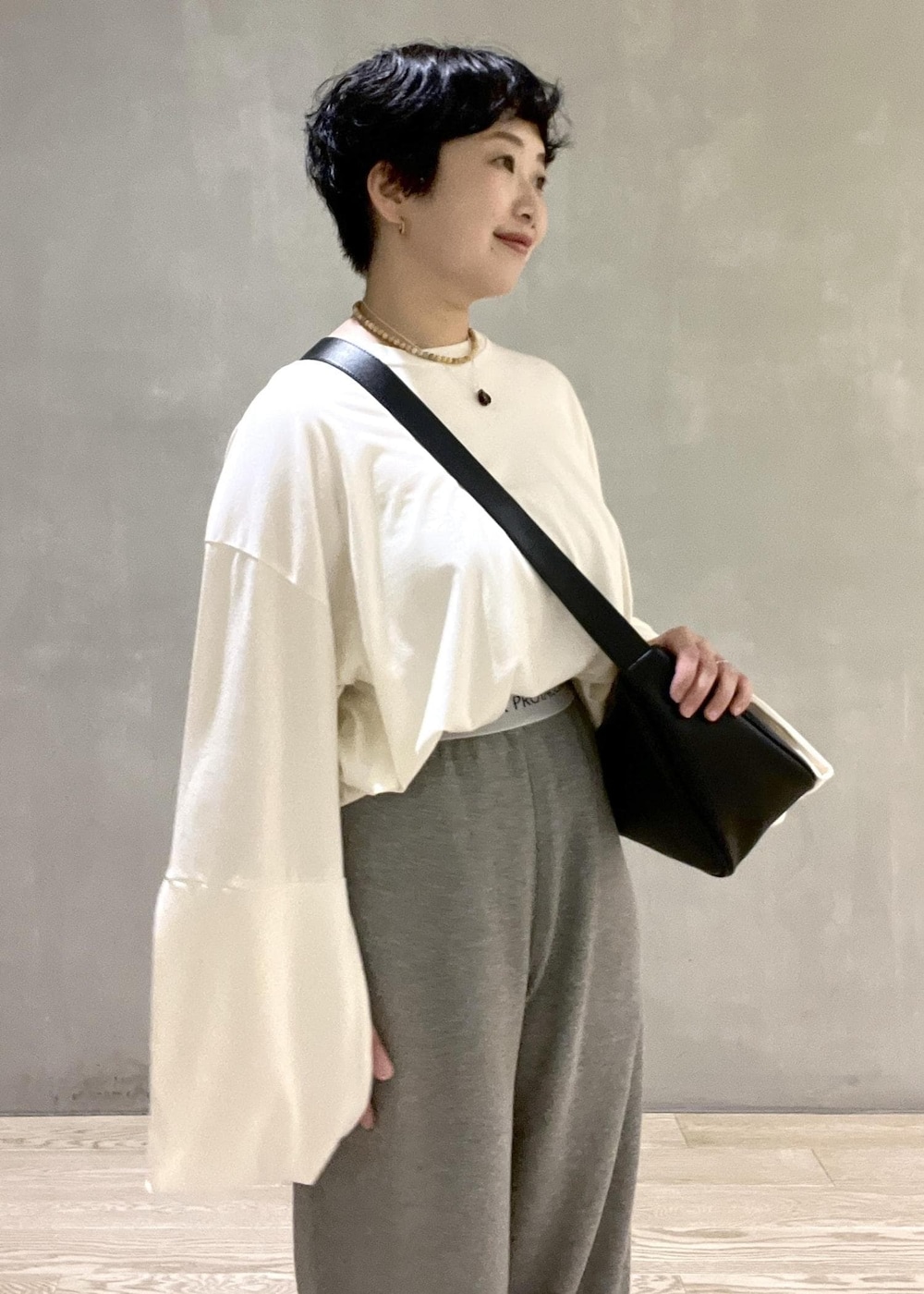 ブラック系のショルダーバッグ、ホワイト系のTシャツ/カットソー、ホワイト系のパンプスを着用したレディースの夏コーディネートの4枚目の写真