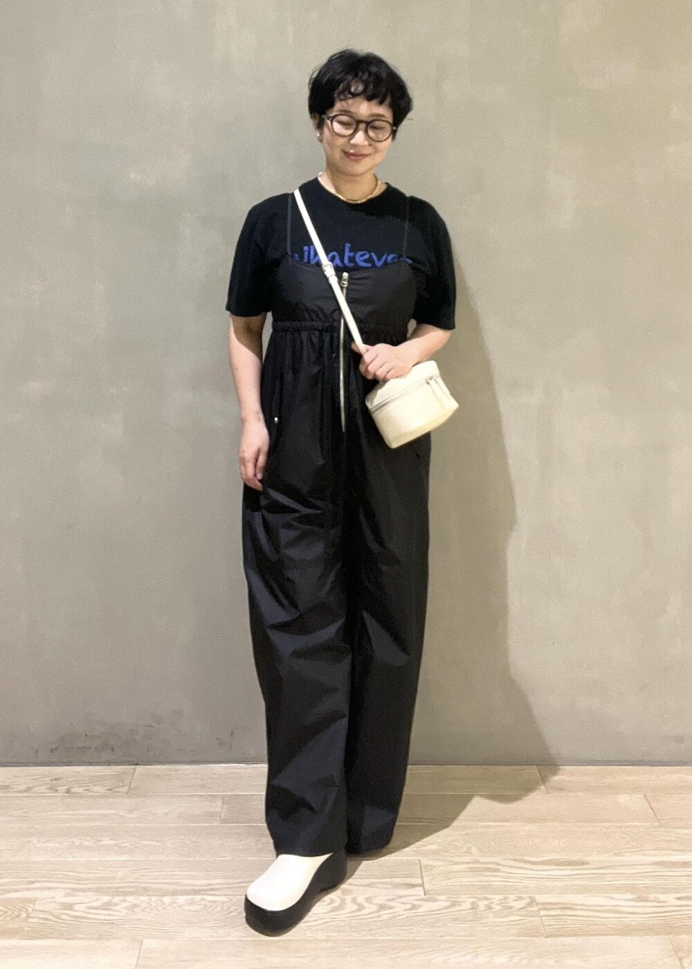 ホワイト系のショルダーバッグ、ブラック系のTシャツ/カットソー、ブラック系のつなぎ/オールインワンを着用したレディースの夏コーディネートの4枚目の写真