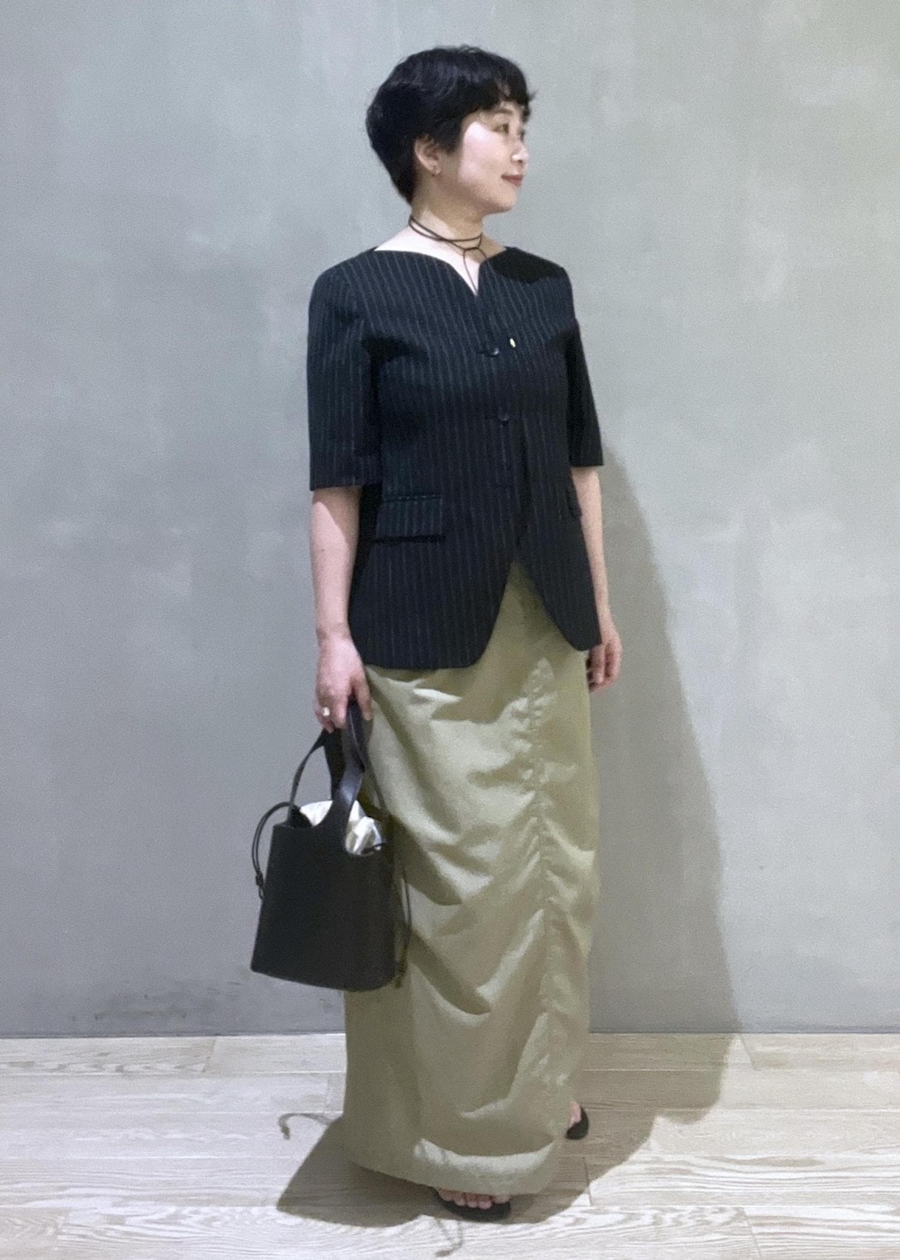 ブラック系のハンドバッグ、ブラック系のノーカラージャケット、ブラック系のサンダルを着用したレディースの夏コーディネートの6枚目の写真