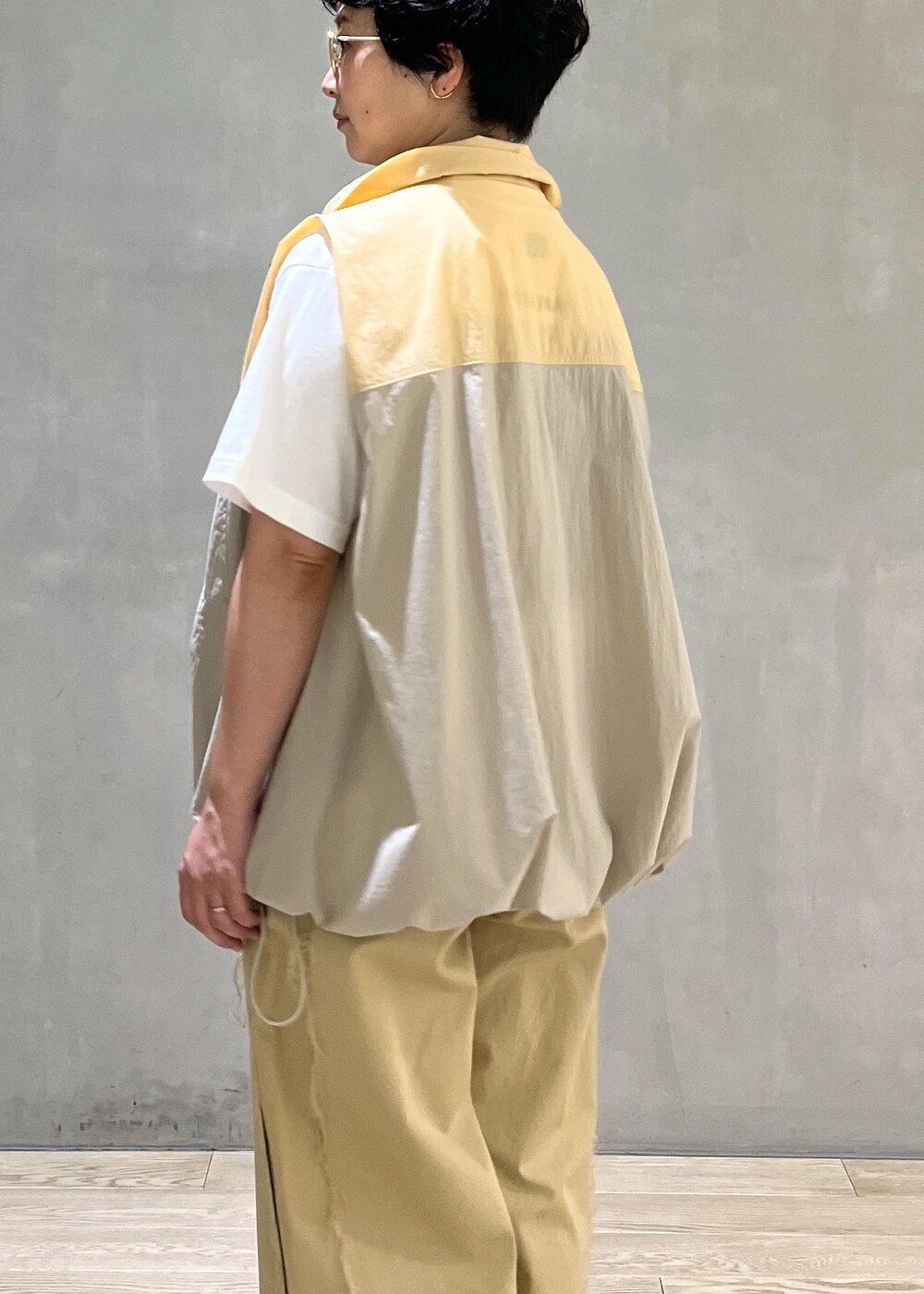 グレー系のハンドバッグ、ホワイト系のTシャツ/カットソー、ベージュ系のブルゾンを着用したレディースの夏コーディネートの6枚目の写真