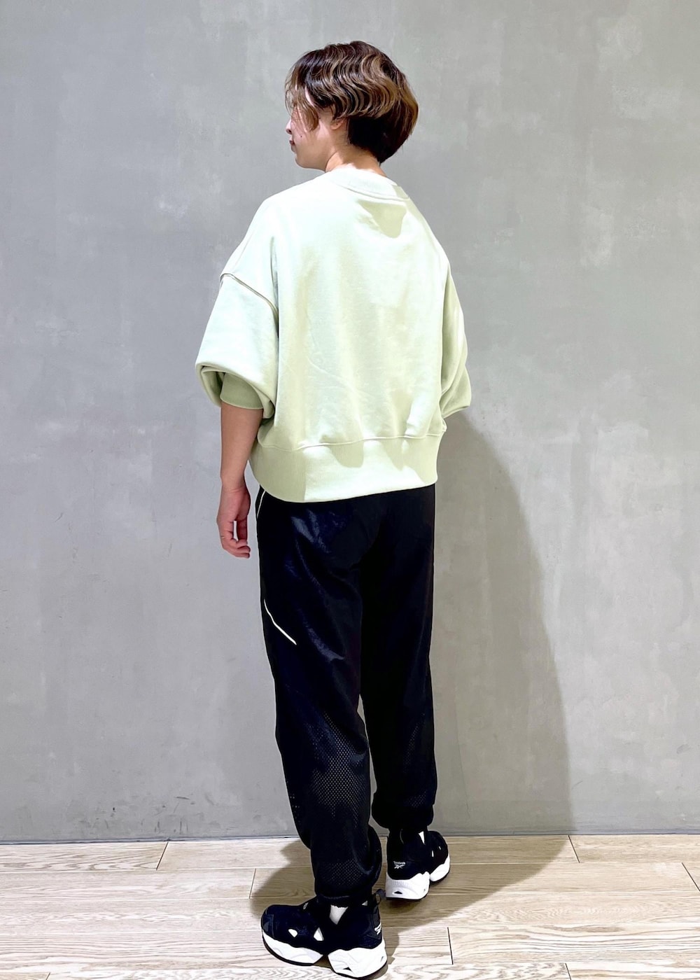 グリーン系のスウェット、ブラック系のスニーカー、ブラック系のその他パンツを着用したレディースの春コーディネートの2枚目の写真