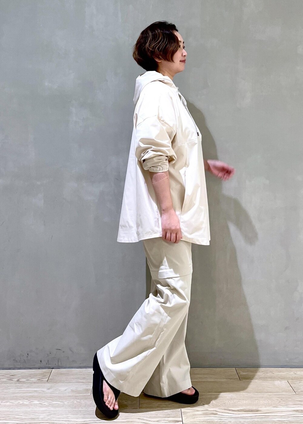 ホワイト系のパーカー、グレー系のその他パンツ、ブラック系のサンダルを着用したレディースの春コーディネートの3枚目の写真