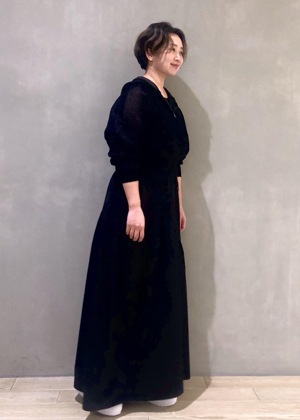 ホワイト系のスニーカー、ブラック系のワンピース、ブラック系のパーカーを着用したレディースの冬コーディネートの2枚目の写真