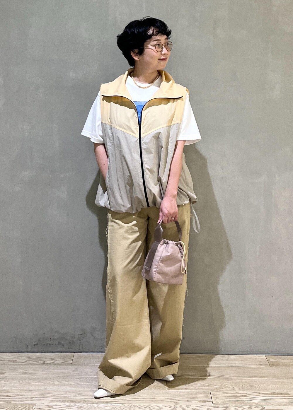 グレー系のハンドバッグ、ホワイト系のTシャツ/カットソー、ベージュ系のブルゾンを着用したレディースの夏コーディネートの7枚目の写真