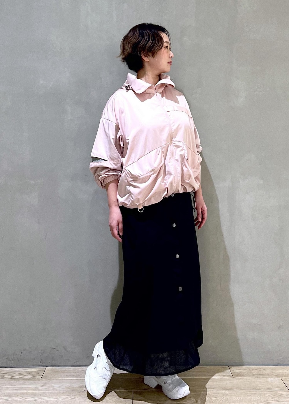 ホワイト系のスニーカー、ピンク系のブルゾン、ブラック系のスカートを着用したレディースの春コーディネートの2枚目の写真