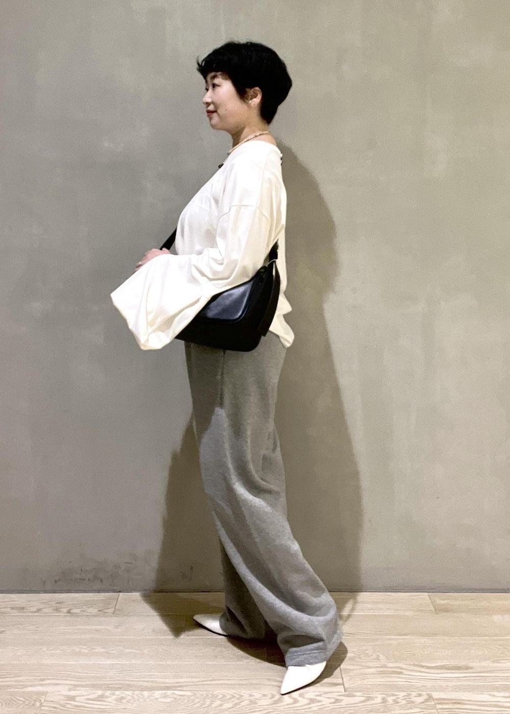 ブラック系のショルダーバッグ、ホワイト系のTシャツ/カットソー、ホワイト系のパンプスを着用したレディースの夏コーディネートの2枚目の写真