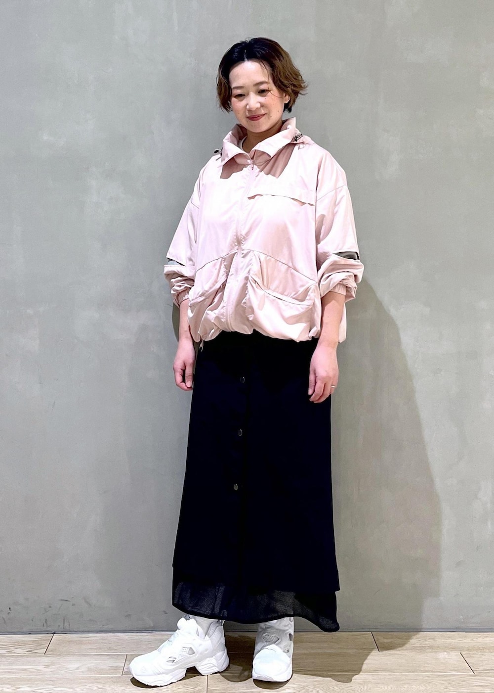 ホワイト系のスニーカー、ピンク系のブルゾン、ブラック系のスカートを着用したレディースの春コーディネートの5枚目の写真
