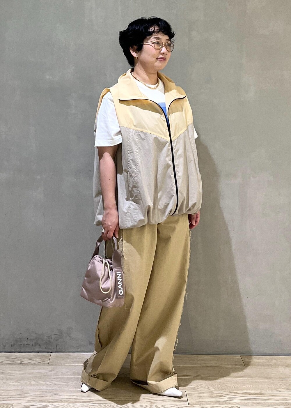 グレー系のハンドバッグ、ホワイト系のTシャツ/カットソー、ベージュ系のブルゾンを着用したレディースの夏コーディネートの2枚目の写真