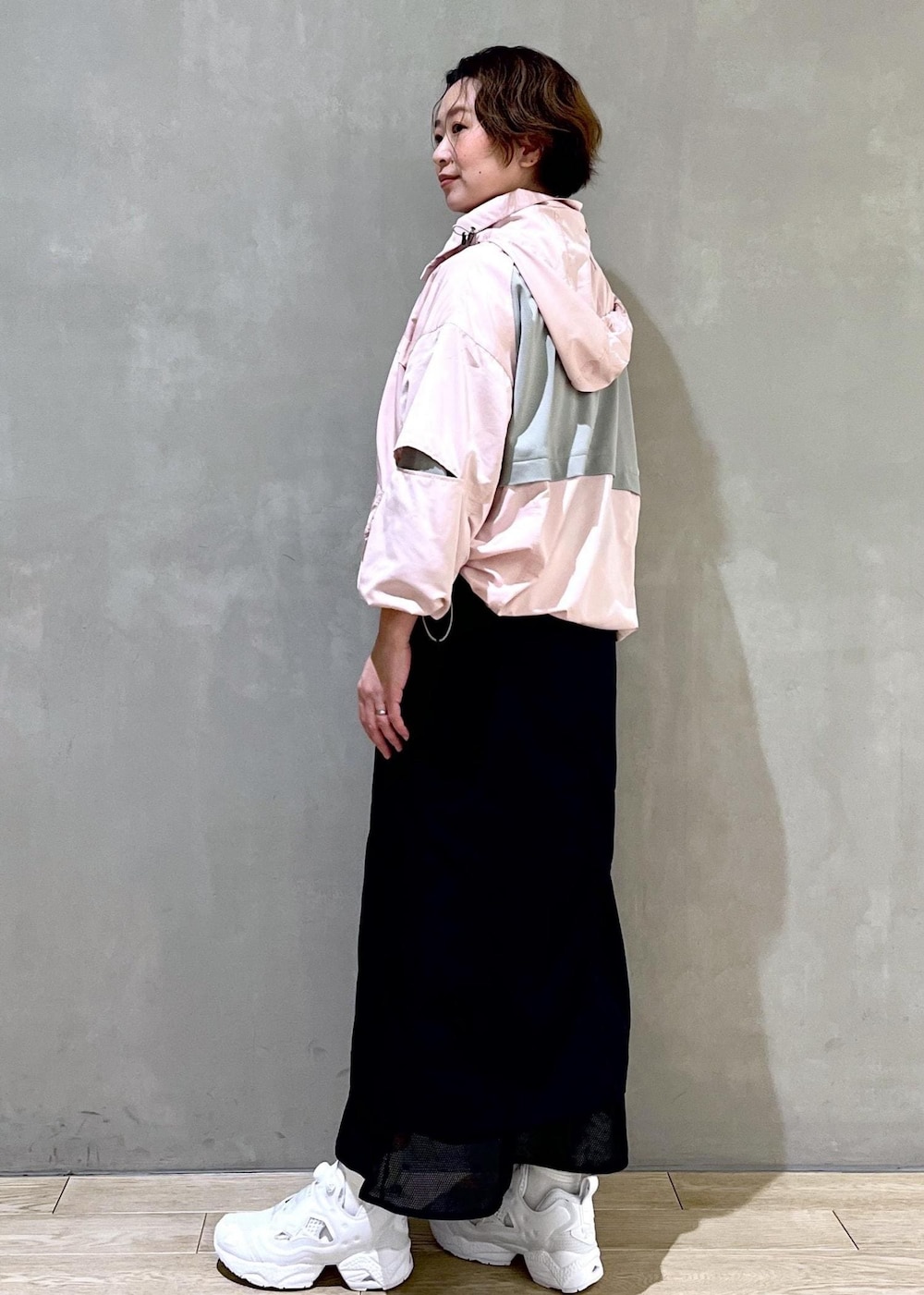 ホワイト系のスニーカー、ピンク系のブルゾン、ブラック系のスカートを着用したレディースの春コーディネートの4枚目の写真