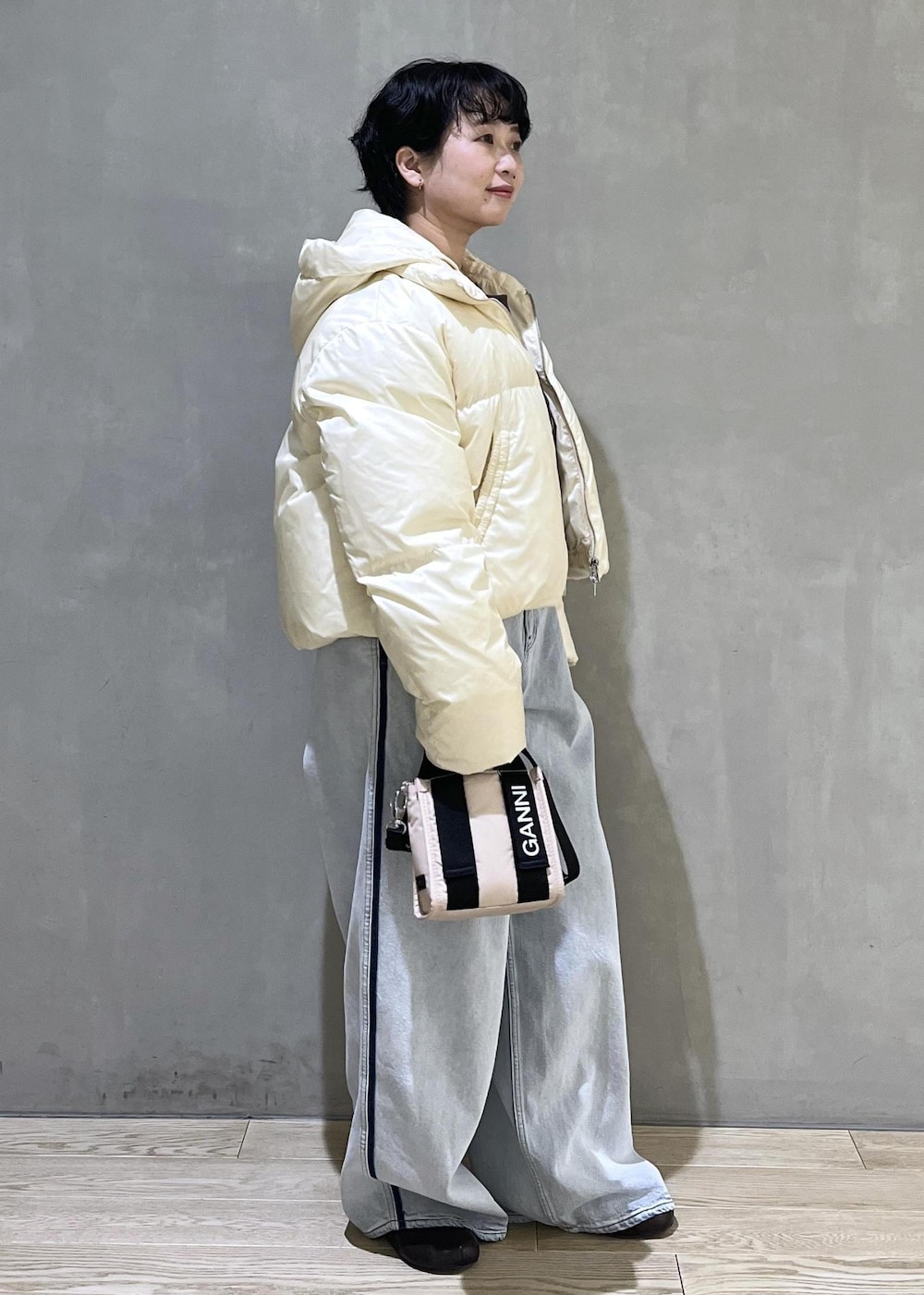 ベージュ系のトートバッグ、ブルー系のデニムパンツ、ブラウン系のスウェットを着用したレディースの秋コーディネートの2枚目の写真