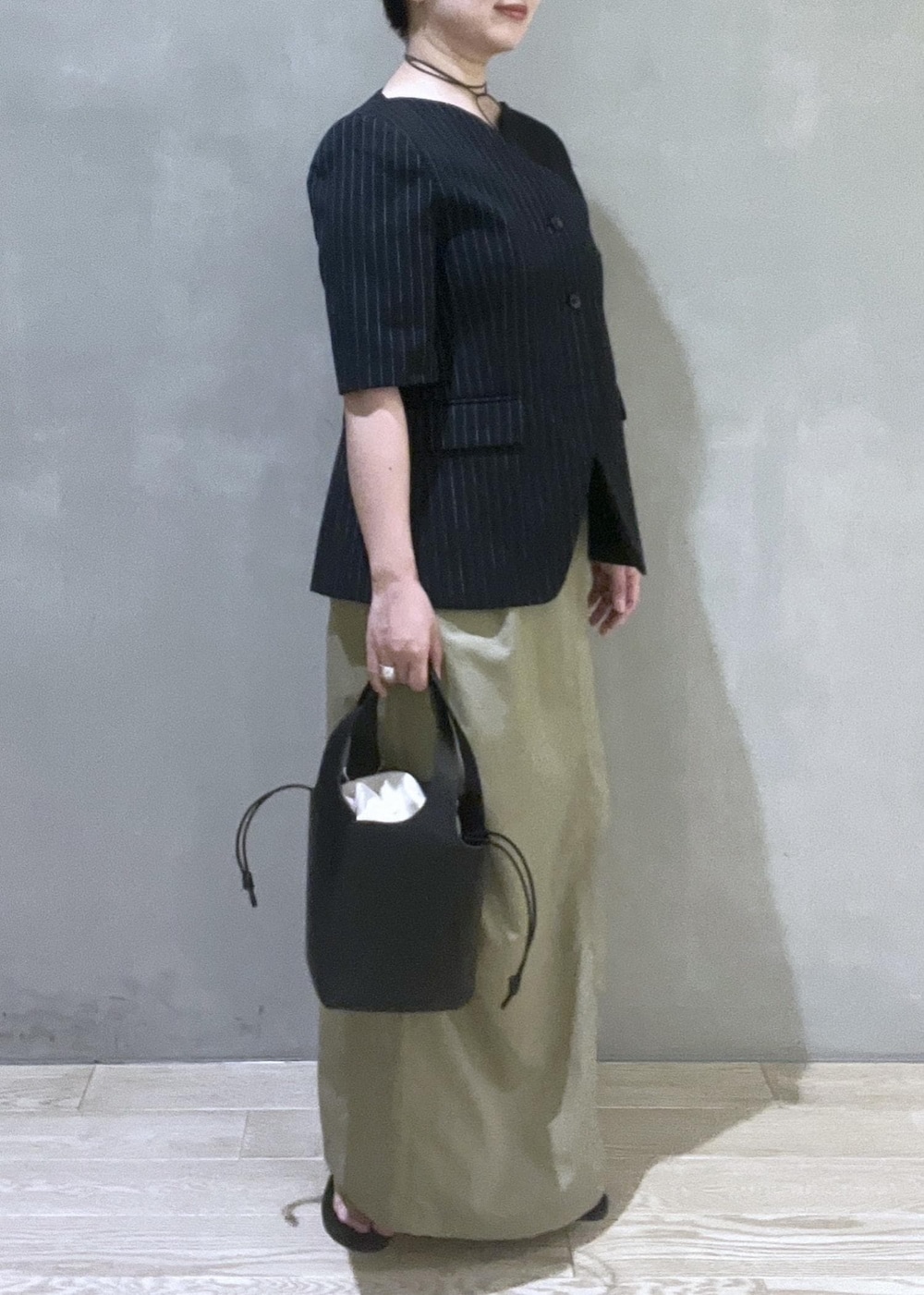 ブラック系のハンドバッグ、ブラック系のノーカラージャケット、ブラック系のサンダルを着用したレディースの夏コーディネートの3枚目の写真