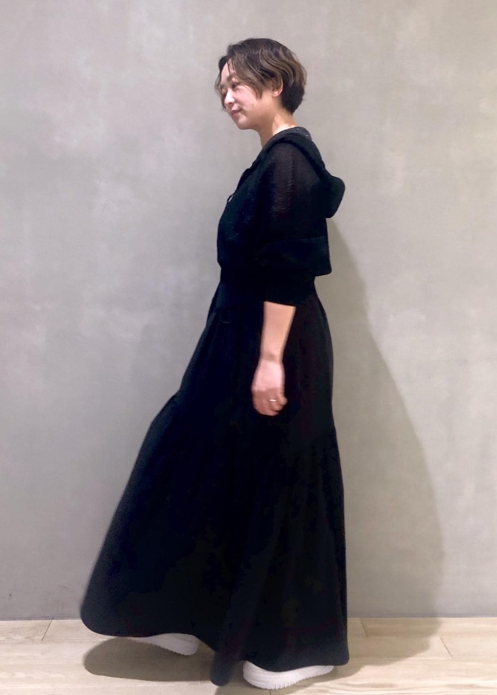 ホワイト系のスニーカー、ブラック系のワンピース、ブラック系のパーカーを着用したレディースの冬コーディネートの3枚目の写真