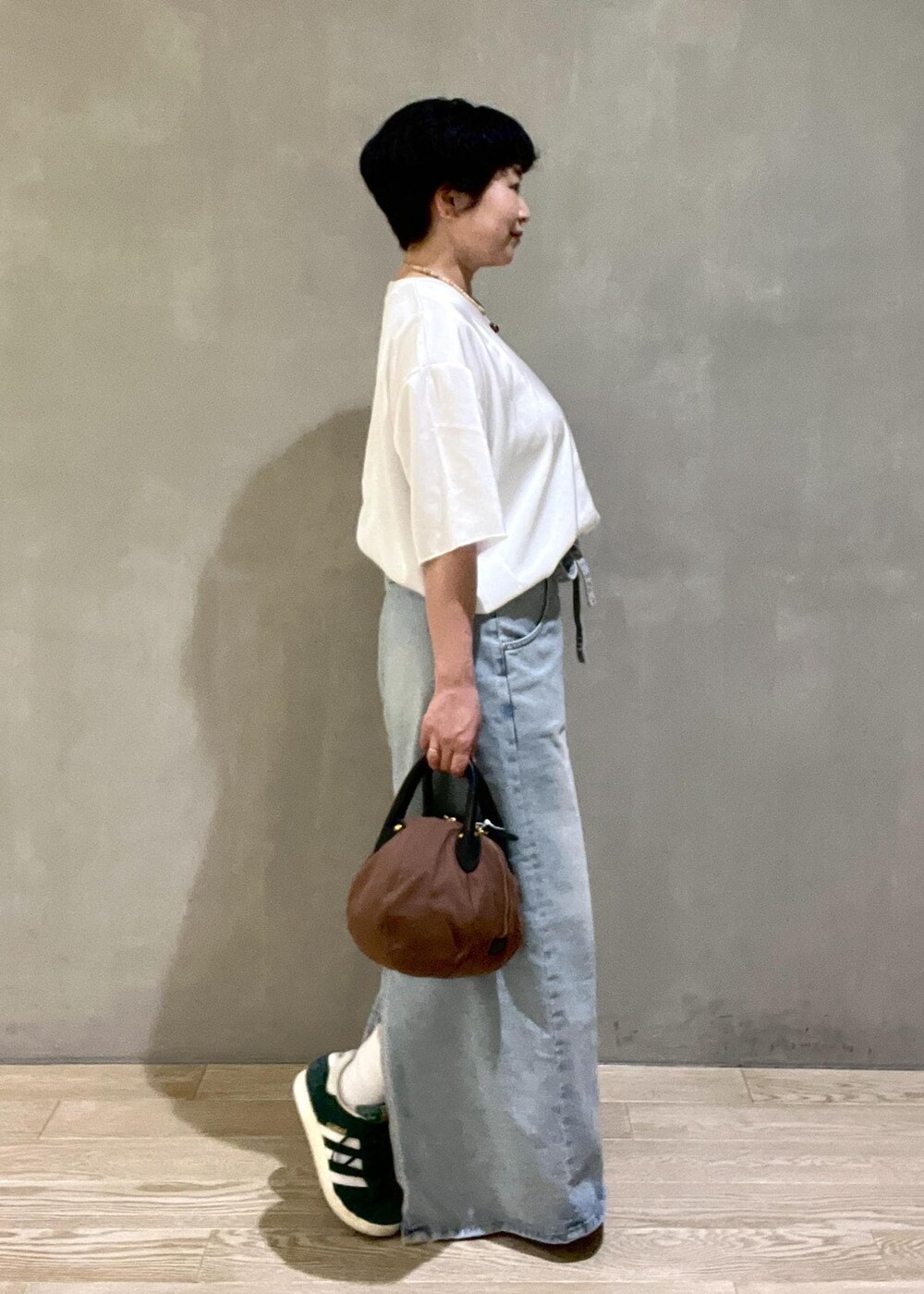 ブラウン系のハンドバッグ、ホワイト系のシャツ/ブラウスを着用したレディースの夏コーディネートの2枚目の写真