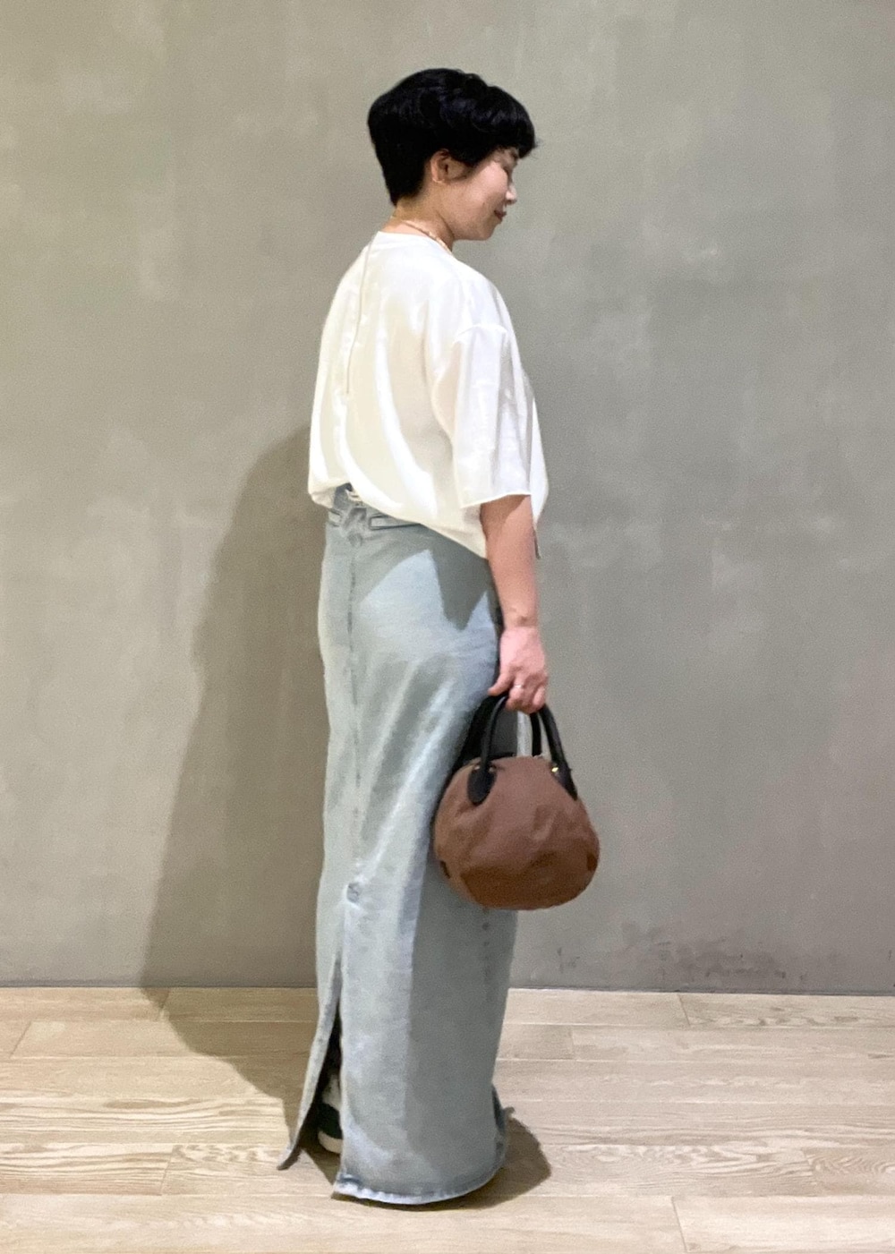 ブラウン系のハンドバッグ、ホワイト系のシャツ/ブラウスを着用したレディースの夏コーディネートの3枚目の写真