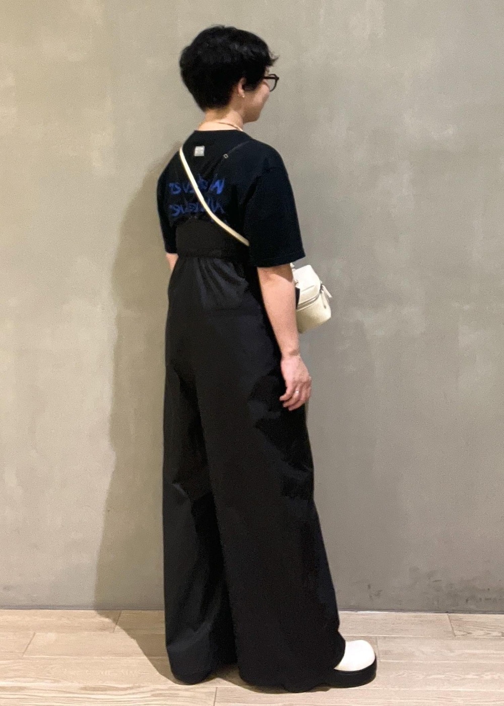 ホワイト系のショルダーバッグ、ブラック系のTシャツ/カットソー、ブラック系のつなぎ/オールインワンを着用したレディースの夏コーディネートの2枚目の写真