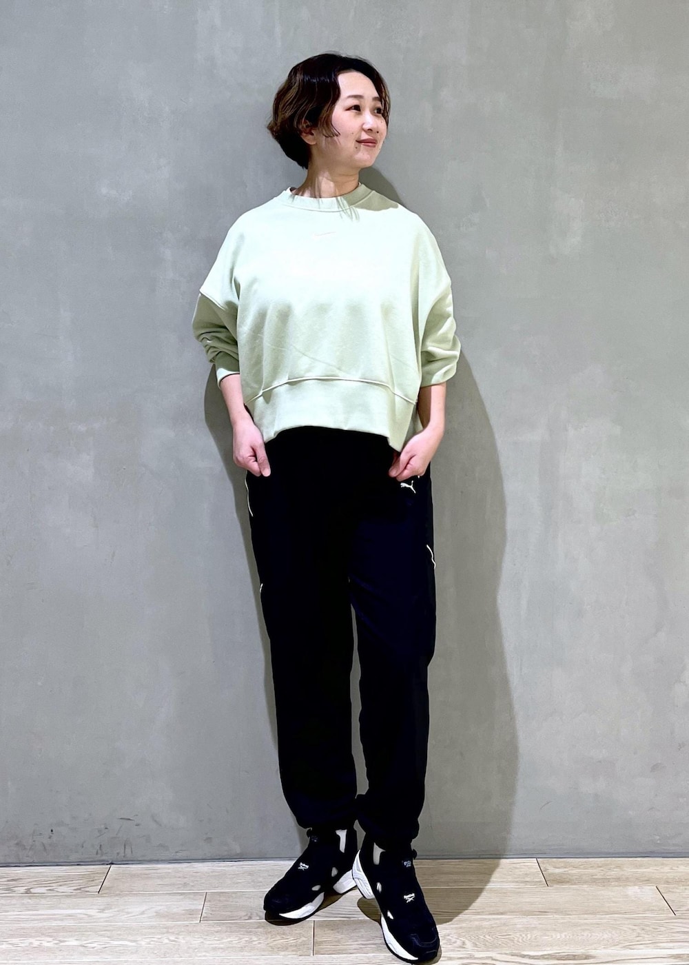 グリーン系のスウェット、ブラック系のスニーカー、ブラック系のその他パンツを着用したレディースの春コーディネートの3枚目の写真
