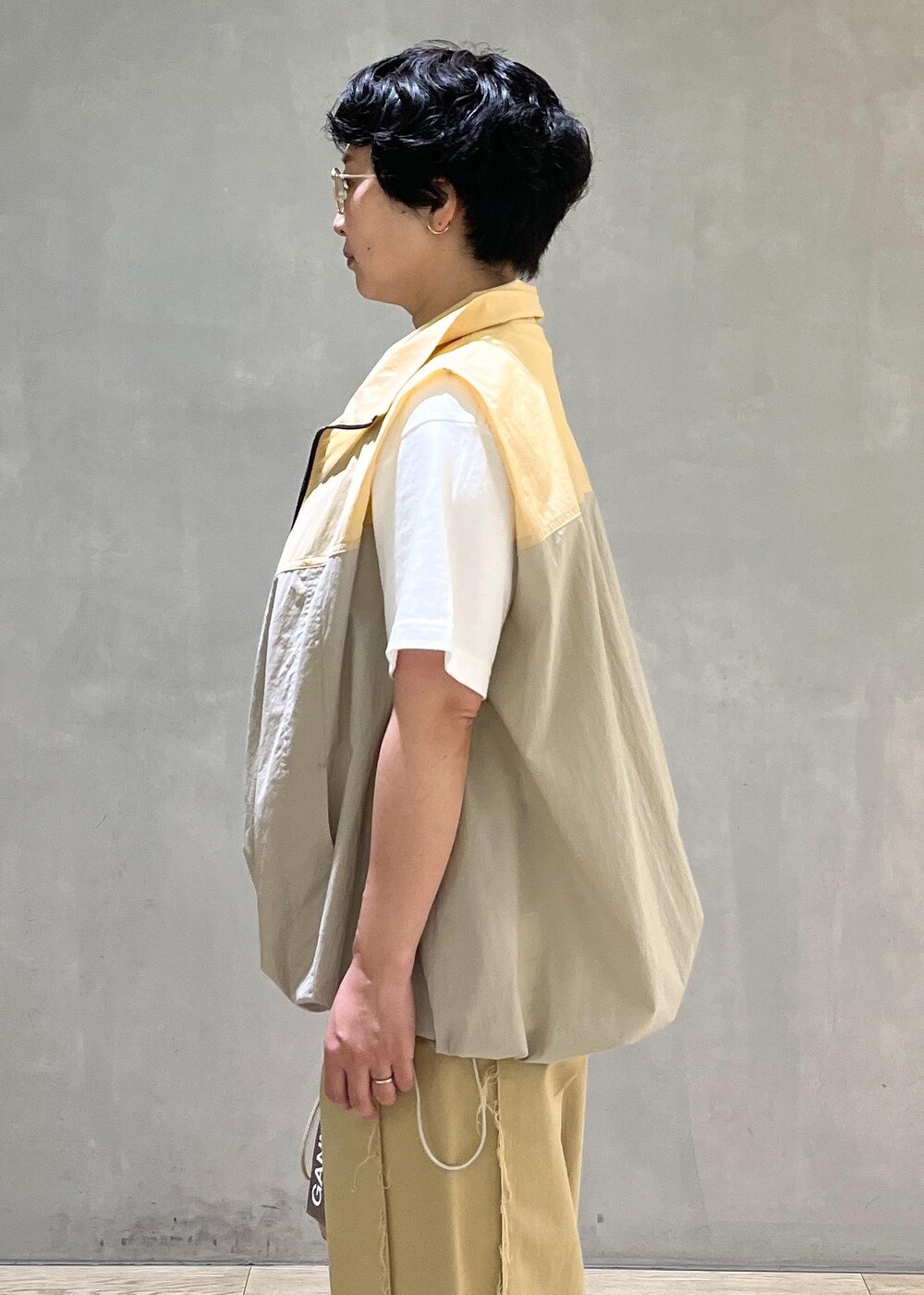 グレー系のハンドバッグ、ホワイト系のTシャツ/カットソー、ベージュ系のブルゾンを着用したレディースの夏コーディネートの5枚目の写真