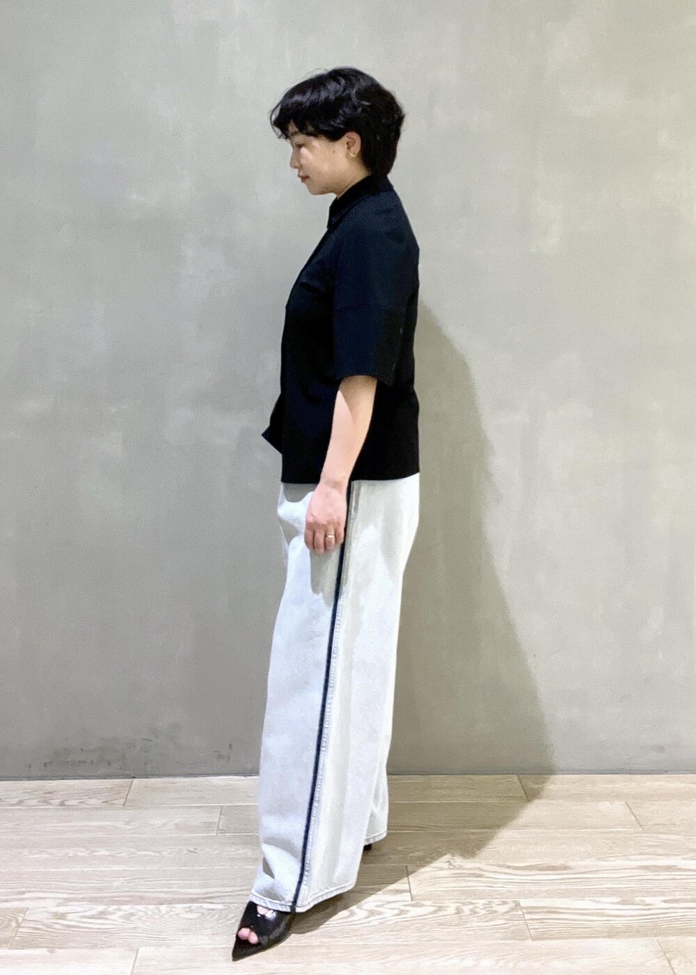 ブルー系のデニムパンツ、ブラック系のシャツ/ブラウス、ブラック系のサンダルを着用したレディースの春コーディネートの3枚目の写真