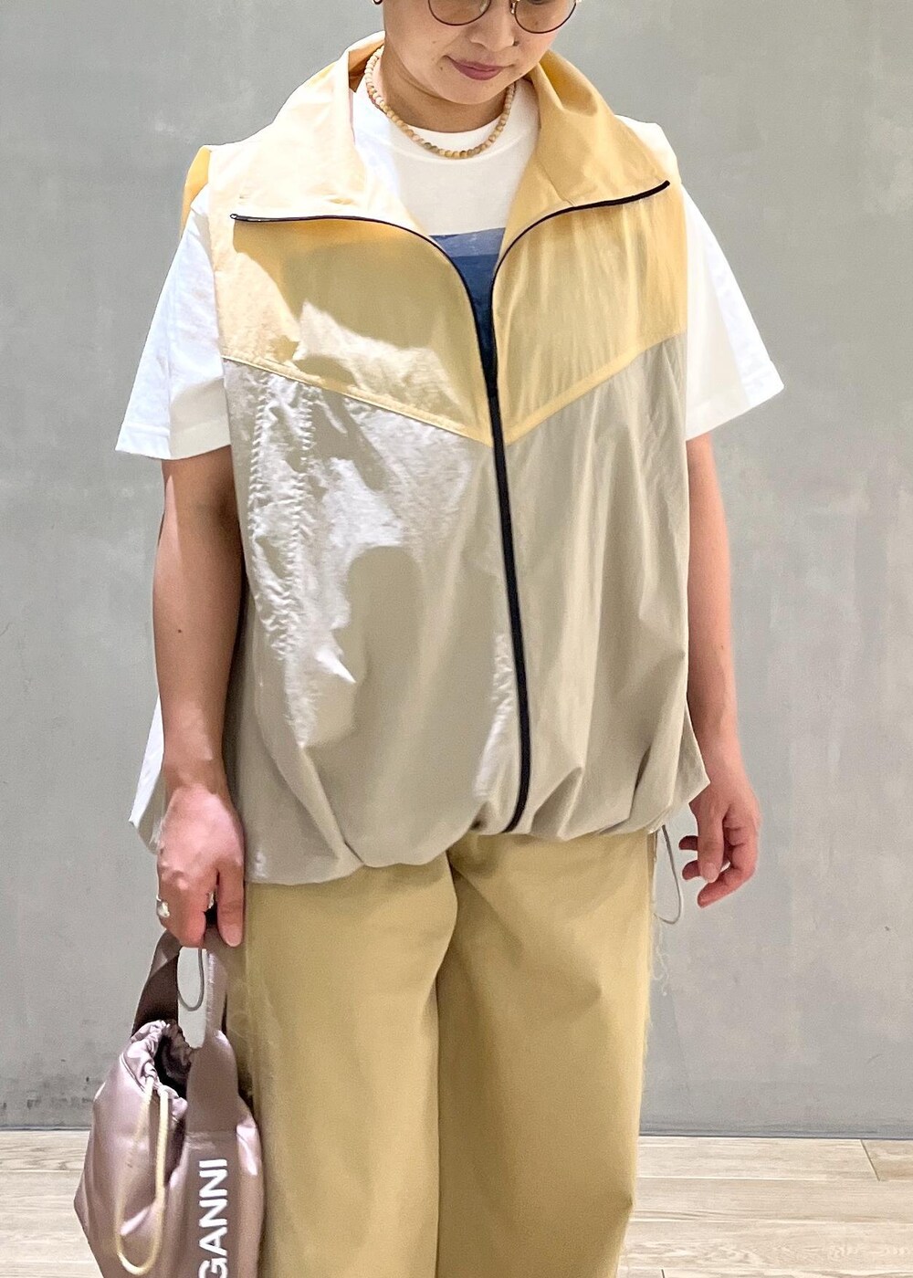 グレー系のハンドバッグ、ホワイト系のTシャツ/カットソー、ベージュ系のブルゾンを着用したレディースの夏コーディネートの4枚目の写真