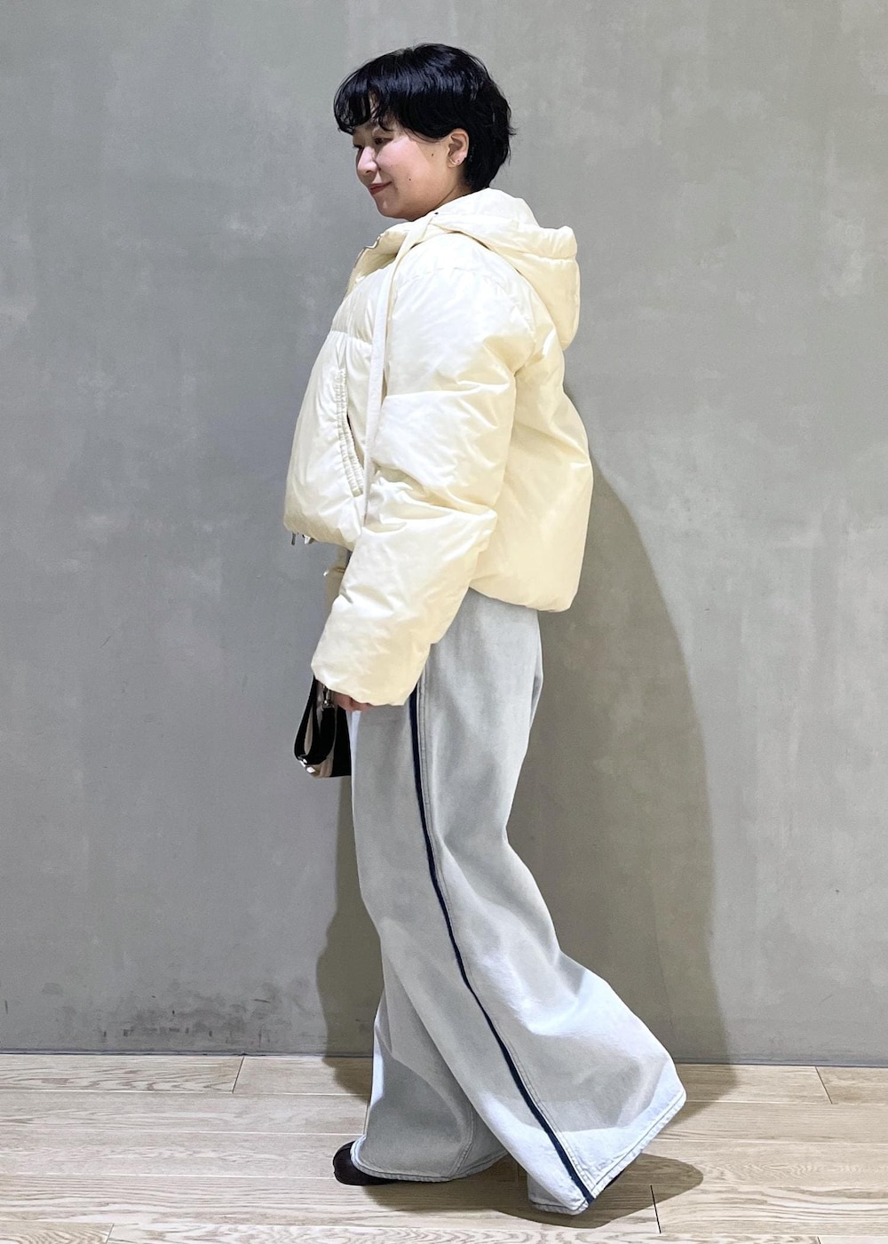 ベージュ系のトートバッグ、ブルー系のデニムパンツ、ブラウン系のスウェットを着用したレディースの秋コーディネートの3枚目の写真