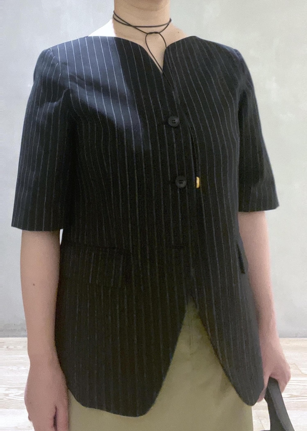 ブラック系のハンドバッグ、ブラック系のノーカラージャケット、ブラック系のサンダルを着用したレディースの夏コーディネートの4枚目の写真