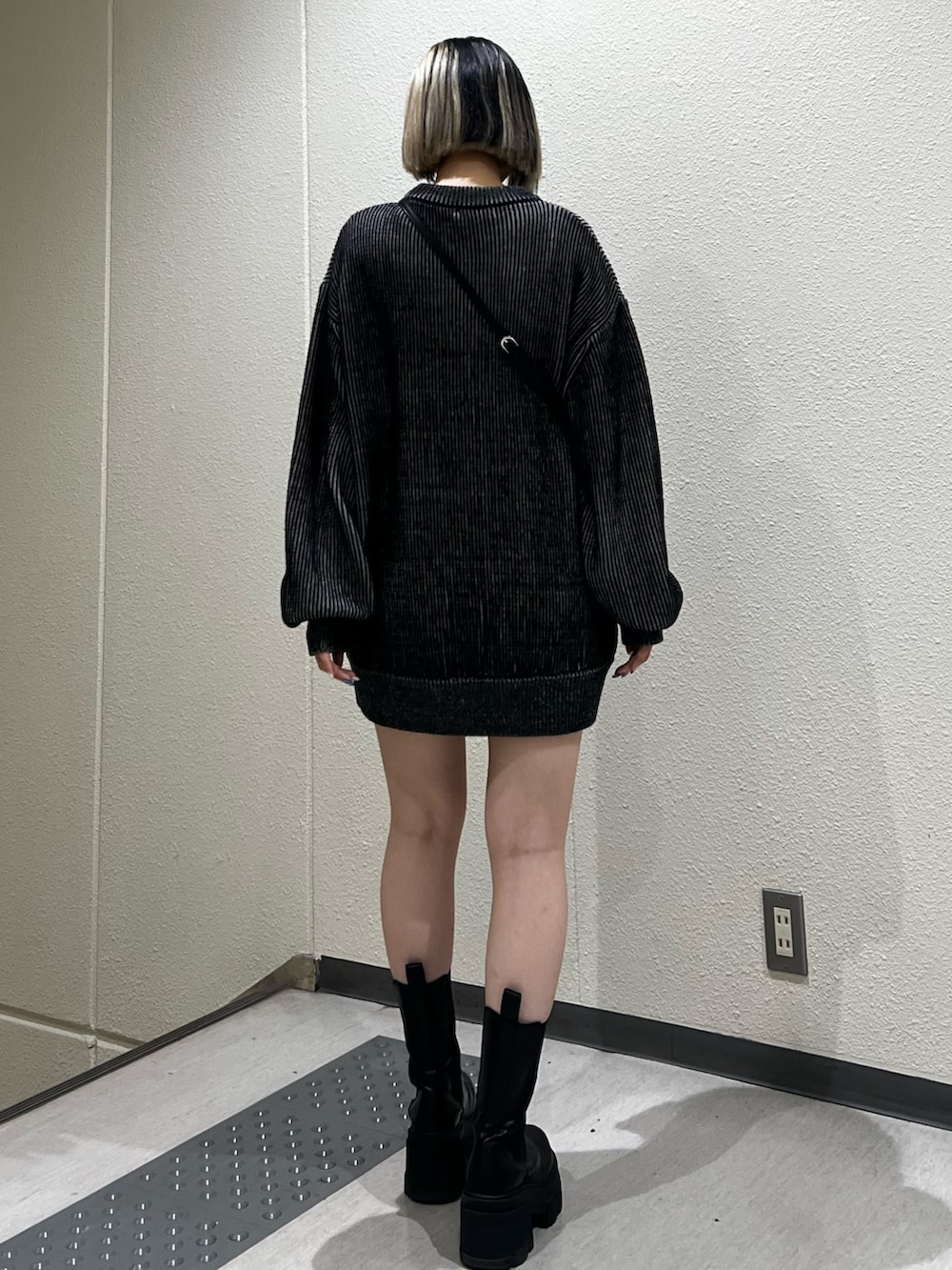 ブラック系のニット/セーター、ブラック系のハンドバッグ、ブラック系のブーツを着用したレディースの秋コーディネートの3枚目の写真