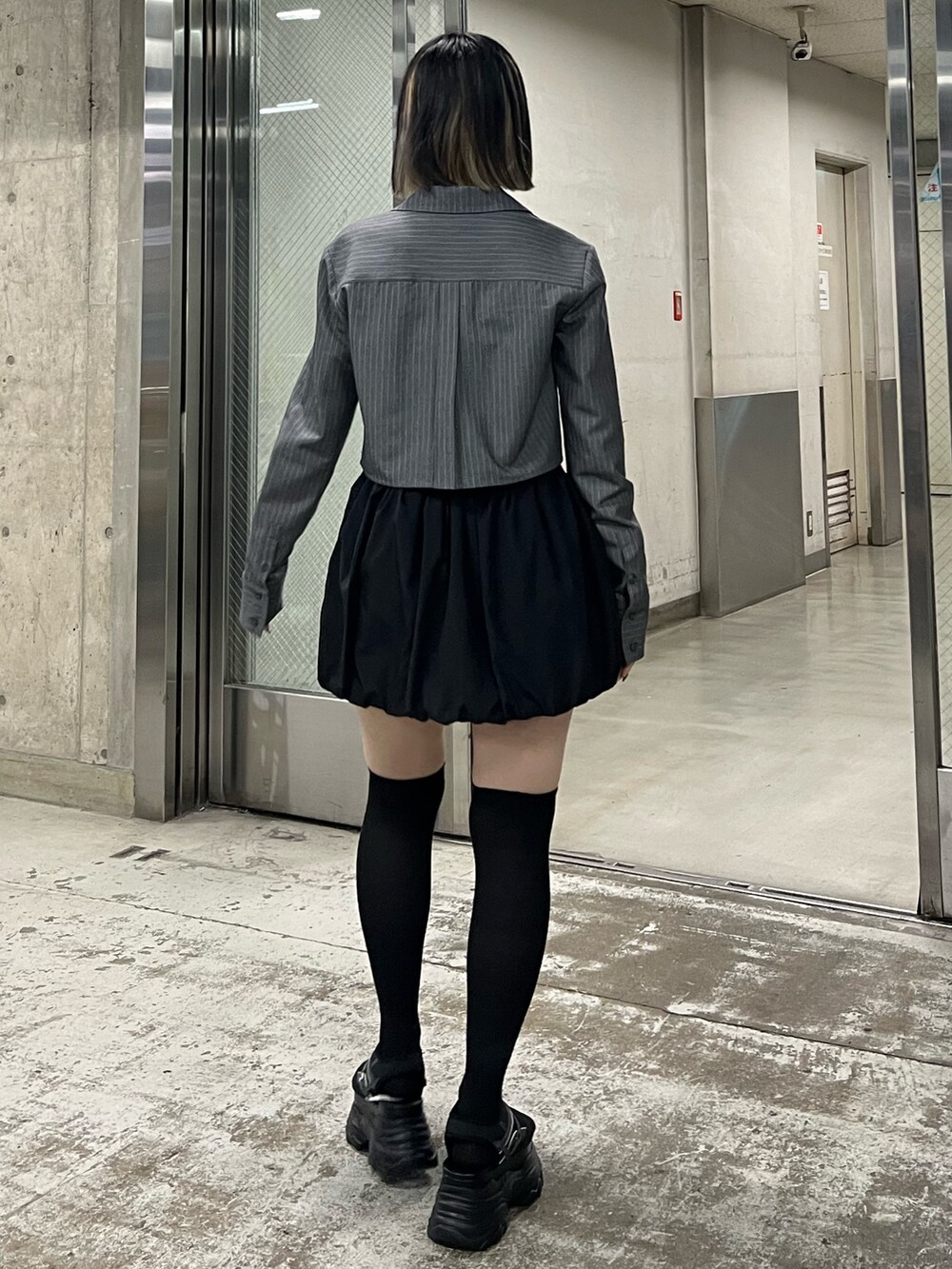 ブラック系のサンダル、ブラック系のスカート、グレー系のシャツ/ブラウスを着用したレディースの春コーディネートの3枚目の写真