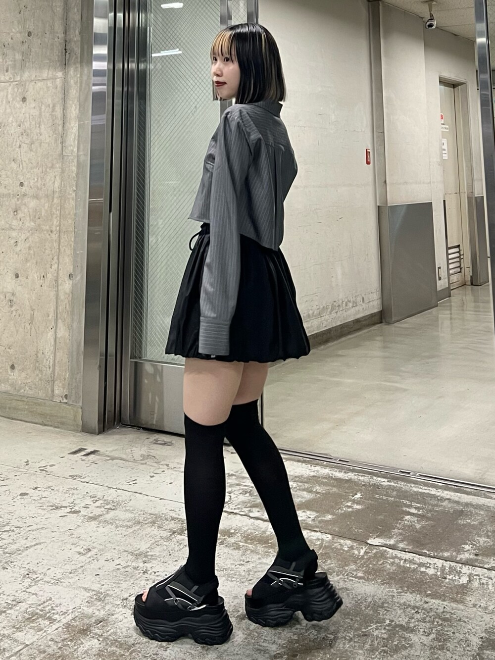 ブラック系のサンダル、ブラック系のスカート、グレー系のシャツ/ブラウスを着用したレディースの春コーディネートの2枚目の写真