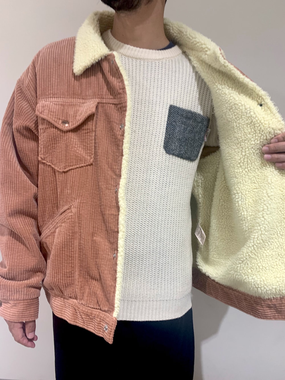 ピンク系のライダースジャケット、ホワイト系のニット/セーター、ブラック系のスウェットパンツを着用したメンズの秋コーディネートの2枚目の写真