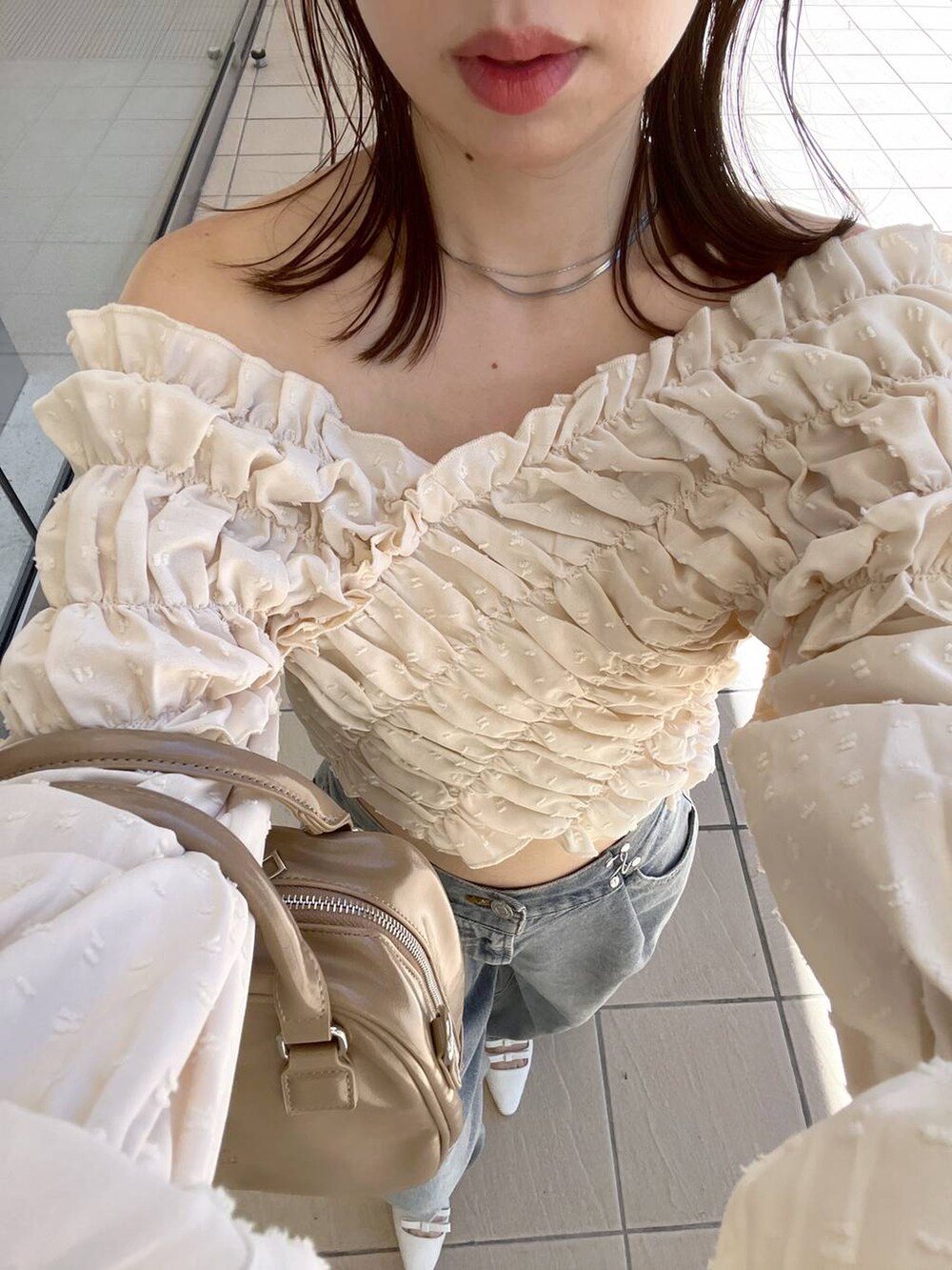 ホワイト系のサンダル、ベージュ系のボストンバッグ、ブルー系のデニムパンツを着用したレディースの夏コーディネートの4枚目の写真