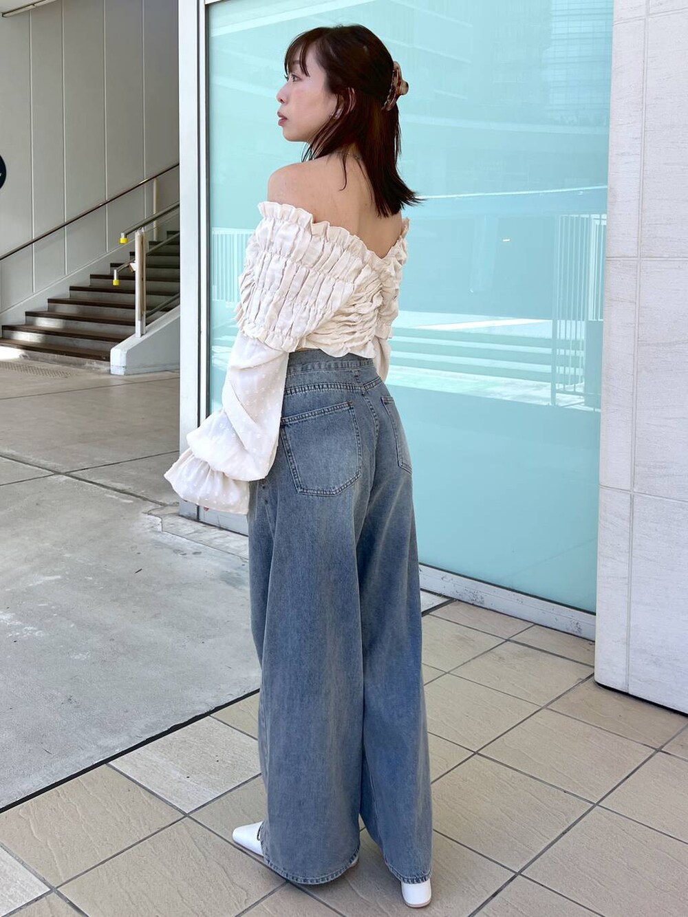 ホワイト系のサンダル、ベージュ系のボストンバッグ、ブルー系のデニムパンツを着用したレディースの夏コーディネートの3枚目の写真