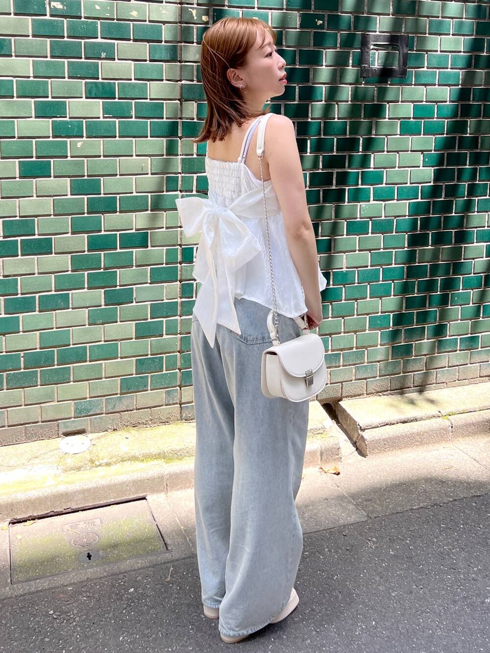 ホワイト系のサンダル、ブルー系のデニムパンツ、ホワイト系のショルダーバッグを着用したレディースの夏コーディネートの2枚目の写真