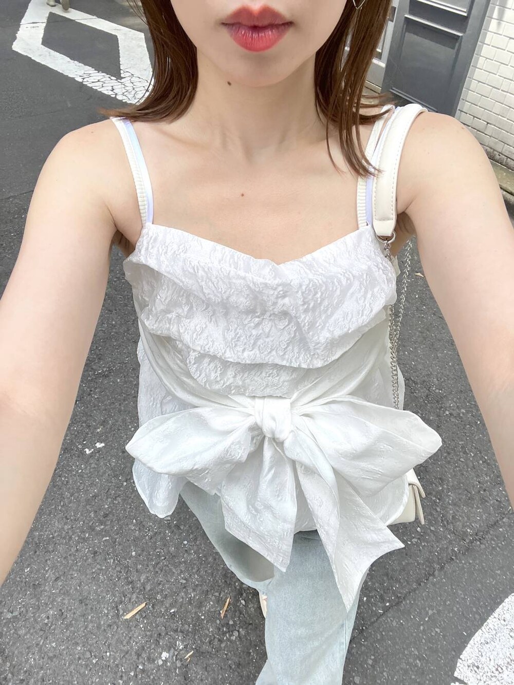 ホワイト系のサンダル、ブルー系のデニムパンツ、ホワイト系のショルダーバッグを着用したレディースの夏コーディネートの4枚目の写真