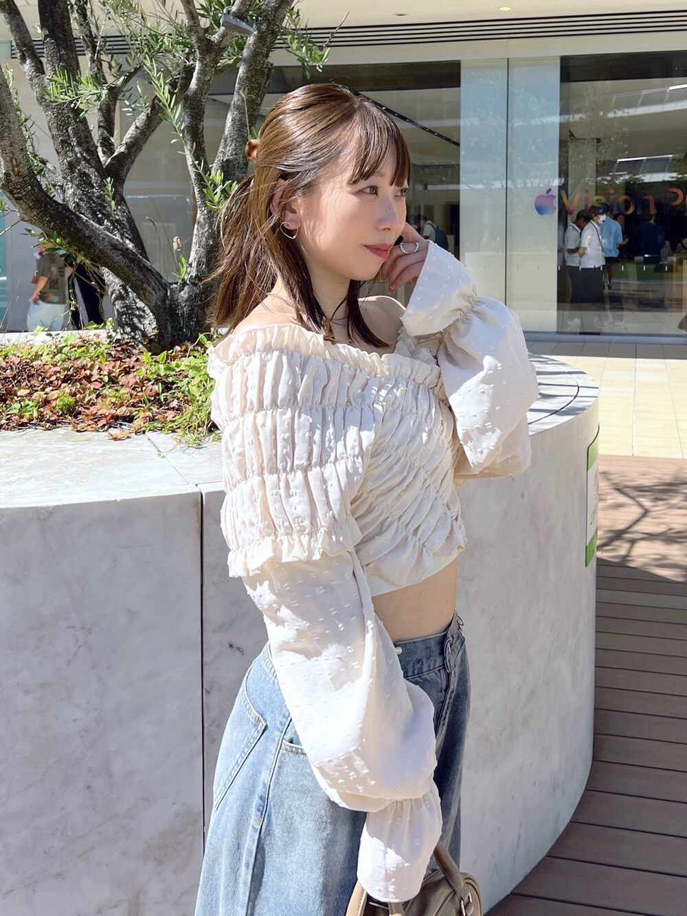ホワイト系のサンダル、ベージュ系のボストンバッグ、ブルー系のデニムパンツを着用したレディースの夏コーディネートの2枚目の写真