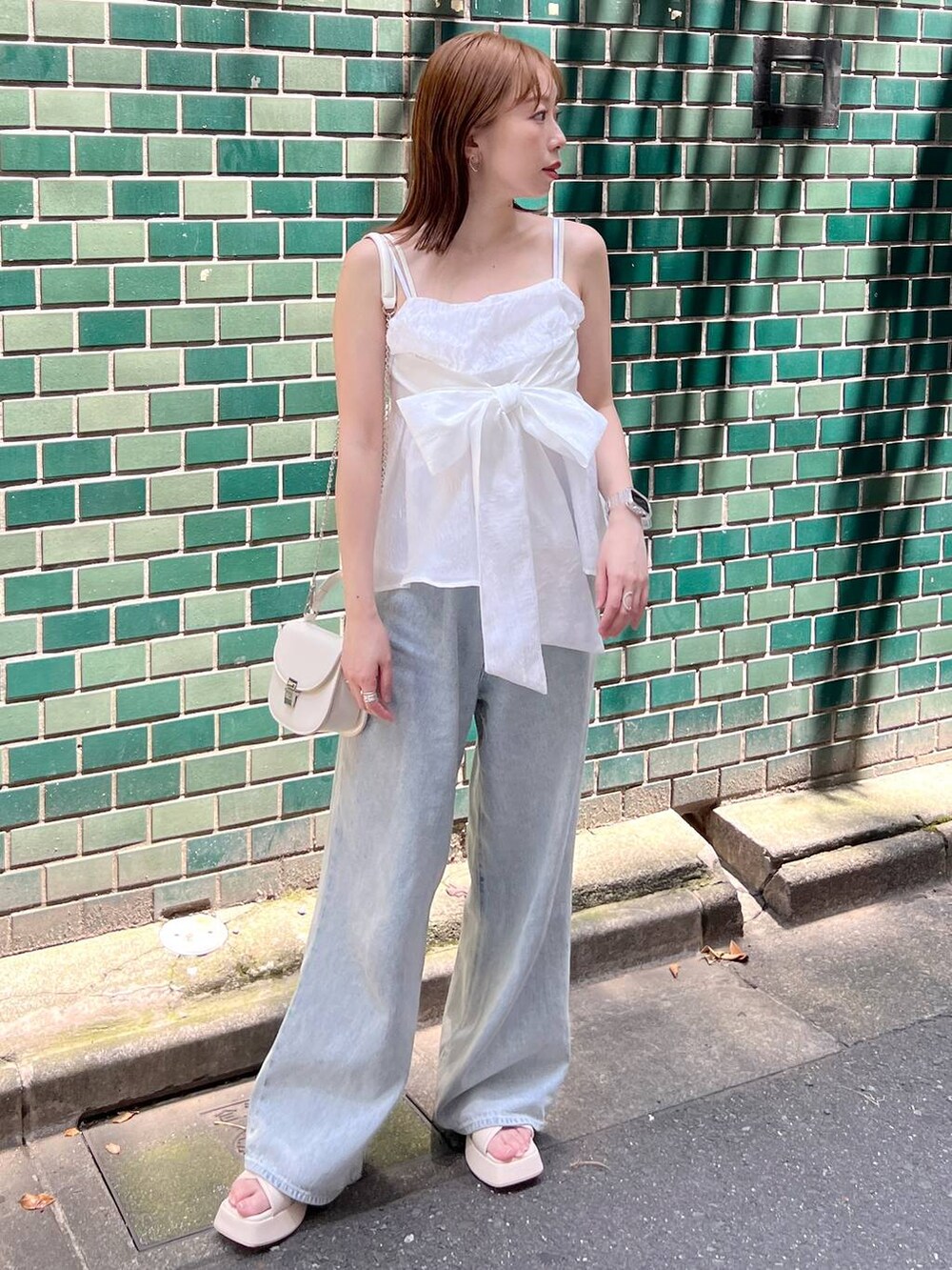 ホワイト系のサンダル、ブルー系のデニムパンツ、ホワイト系のショルダーバッグを着用したレディースの夏コーディネートの3枚目の写真