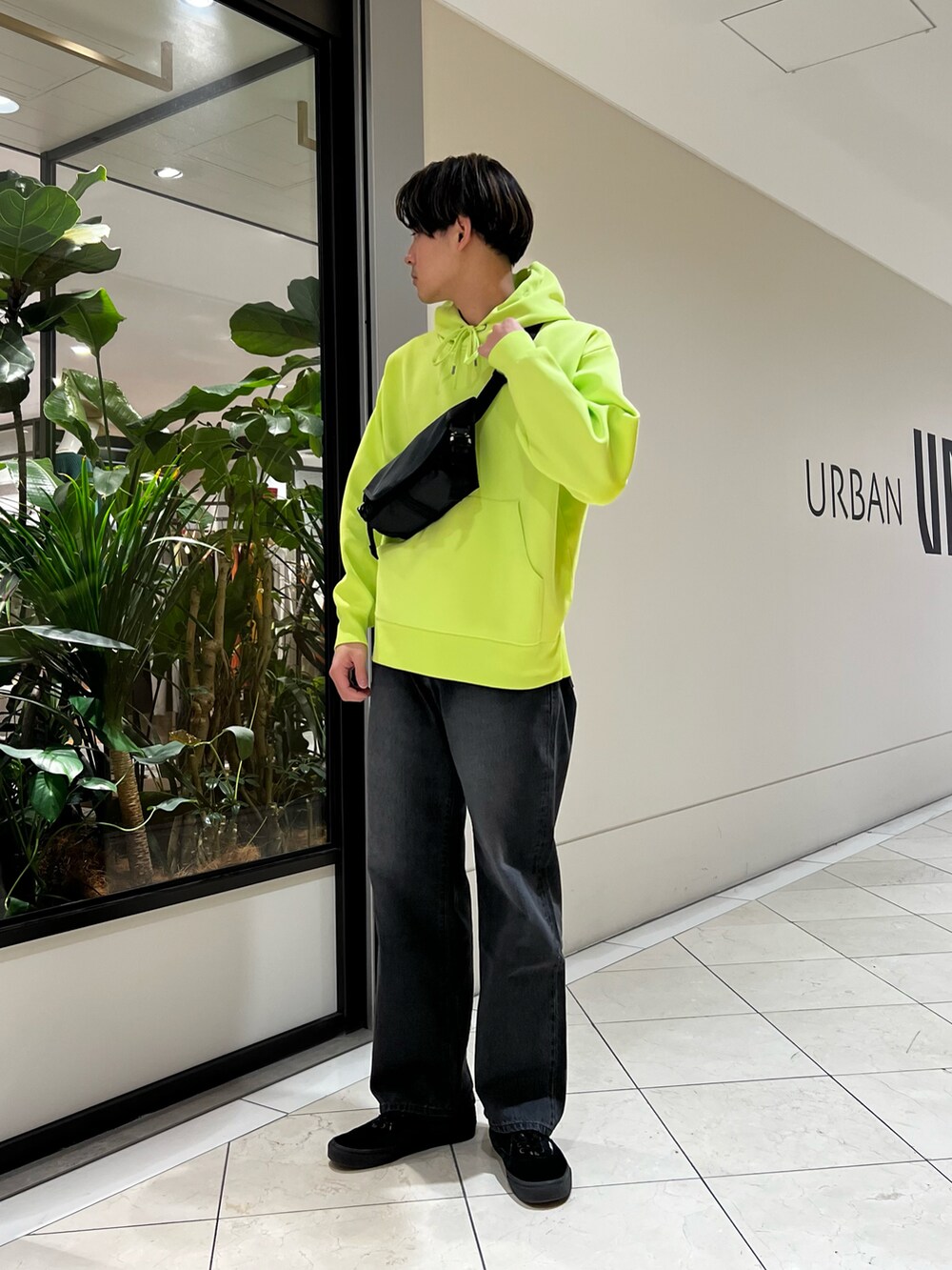 グリーン系のパーカー、ブラック系のショルダーバッグ、ブラック系のデニムパンツを着用したメンズの冬コーディネートの2枚目の写真