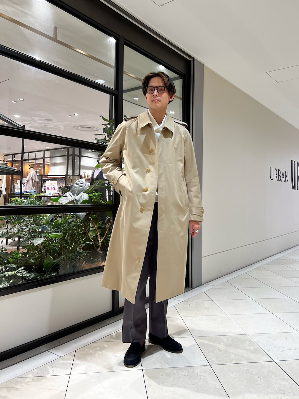 グレー系のスラックス、ベージュ系のトレンチコート、ホワイト系のスウェットを着用したメンズの春コーディネートの3枚目の写真