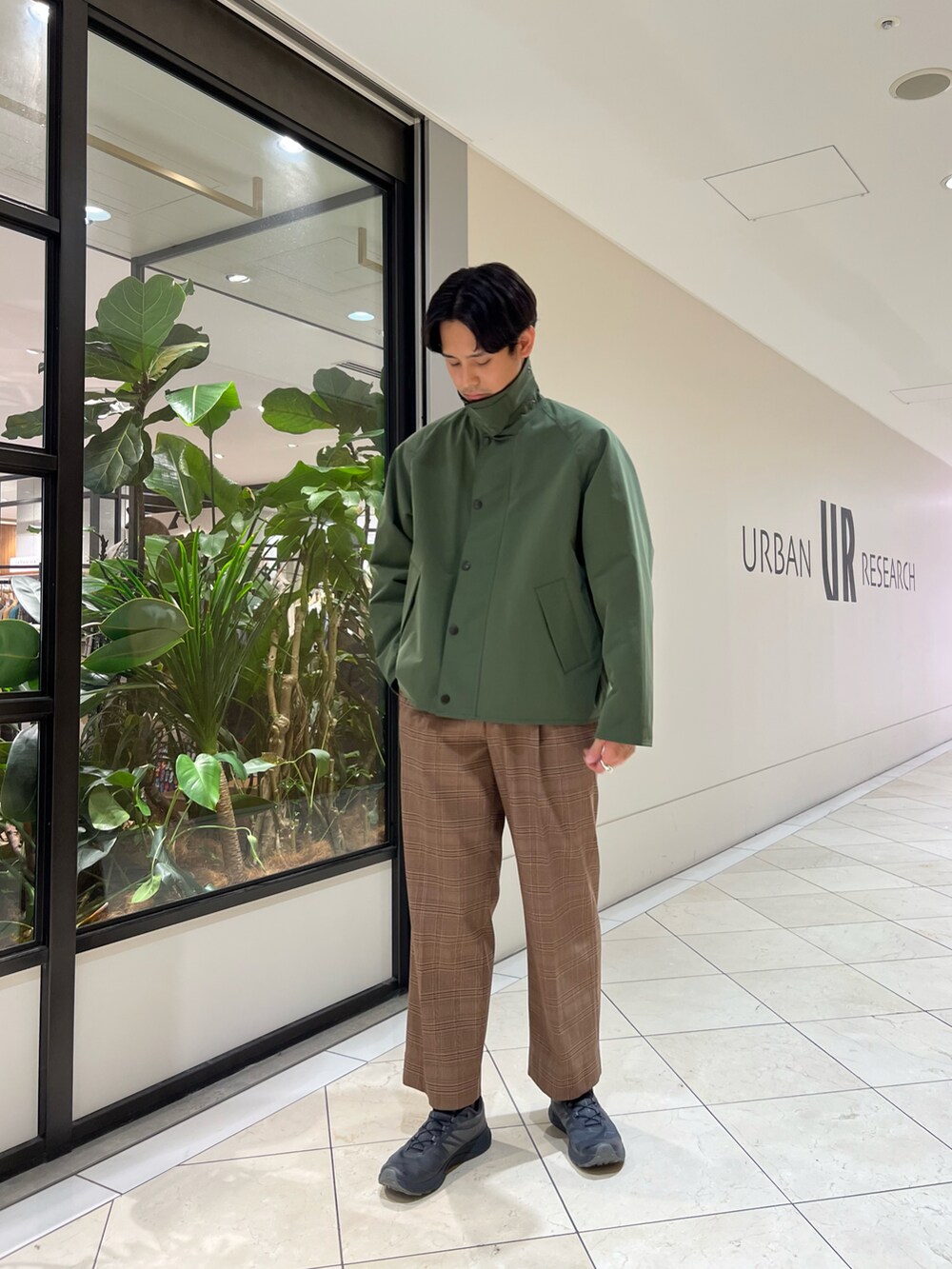 グリーン系のナイロンジャケット、ブラウン系のパンツ、グレー系のスニーカーを着用したメンズの秋コーディネートの3枚目の写真