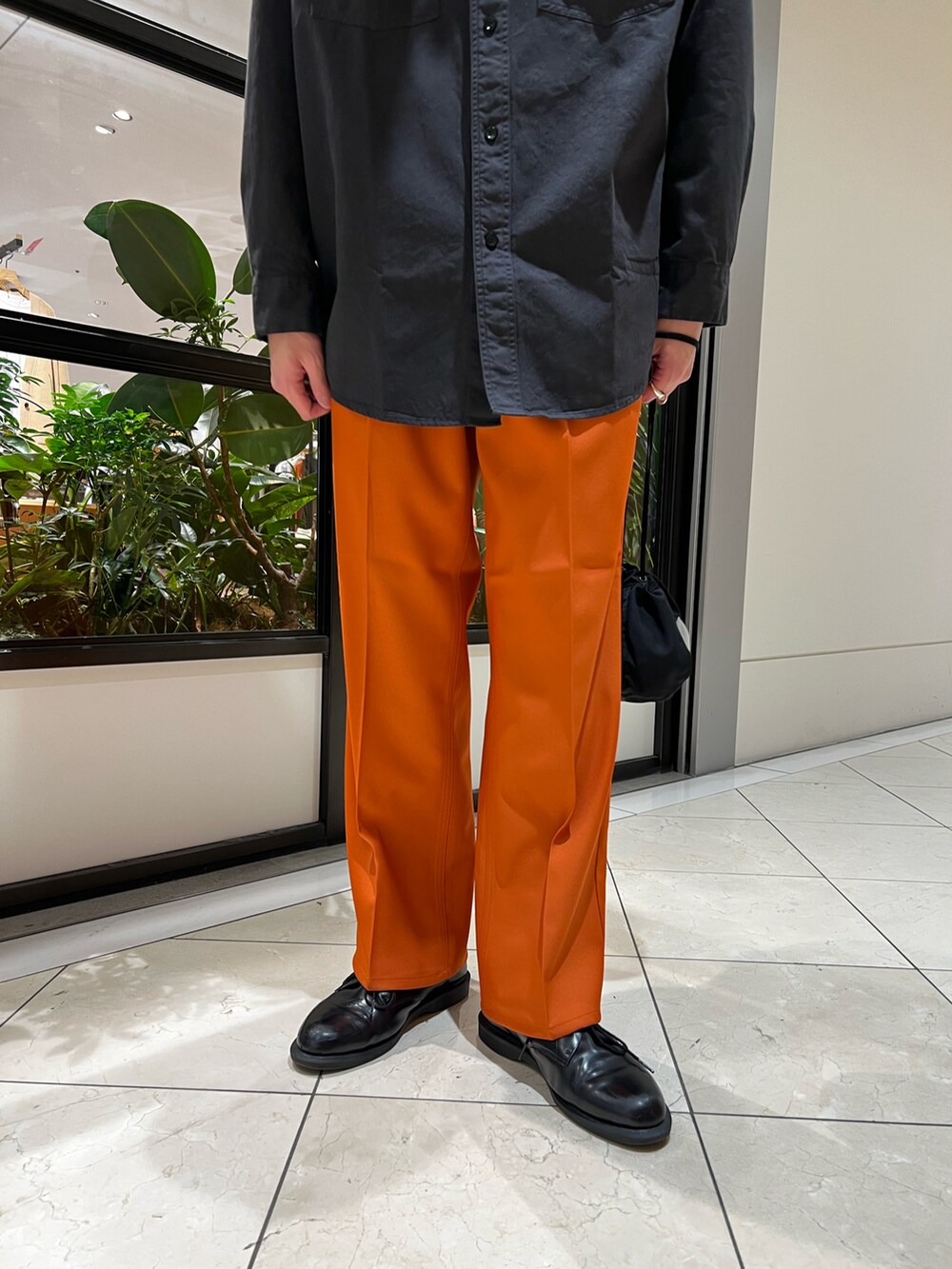 ブラック系のシャツ/ブラウス、ブラック系のハンドバッグ、オレンジ系のその他パンツを着用したメンズの冬コーディネートの2枚目の写真