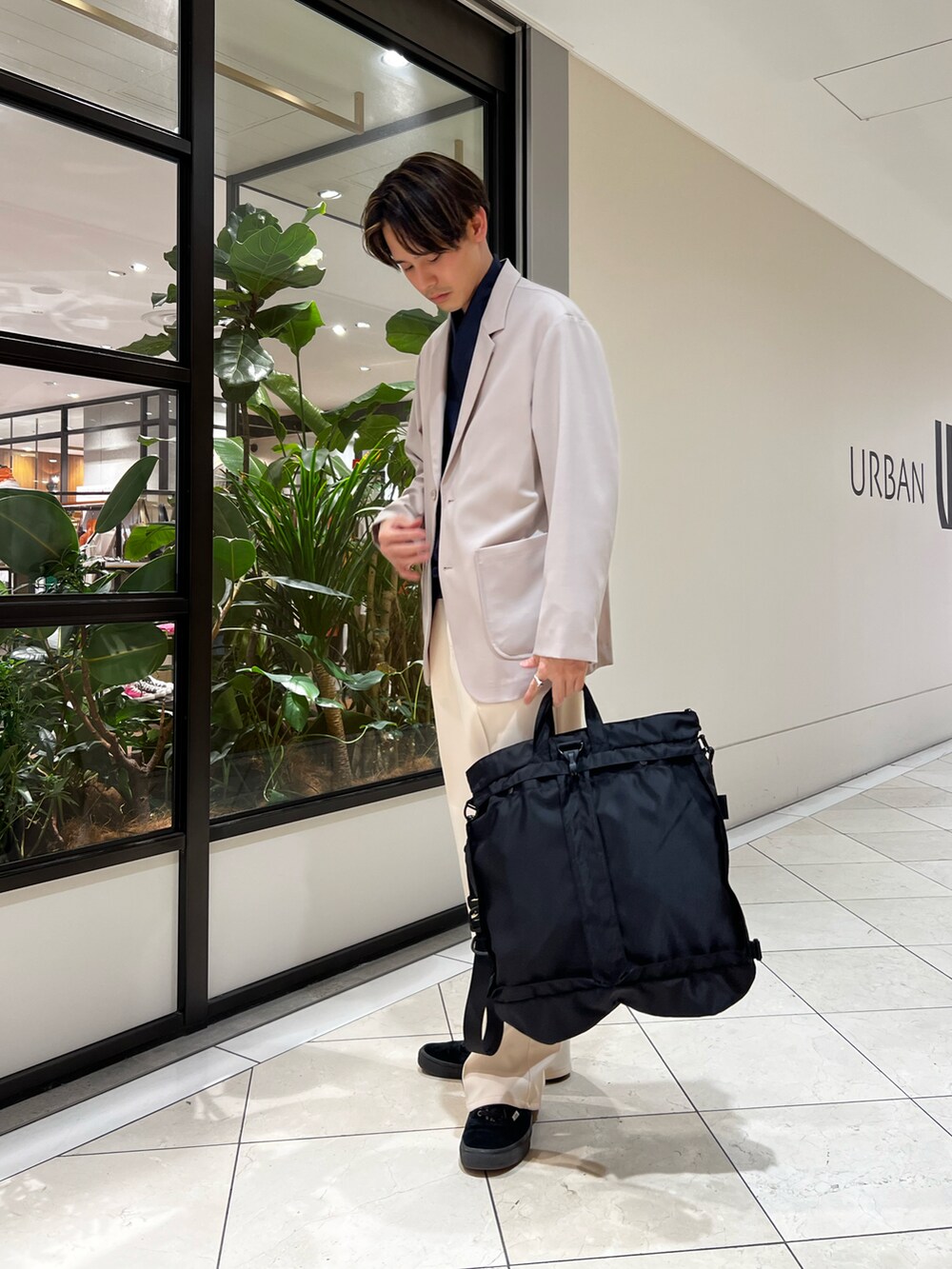 ブルー系のベスト、グレー系のその他アウター、ブラック系のトートバッグを着用したメンズの春コーディネートの3枚目の写真