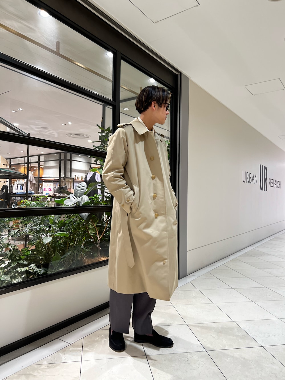 グレー系のスラックス、ベージュ系のトレンチコート、ホワイト系のスウェットを着用したメンズの春コーディネートの4枚目の写真