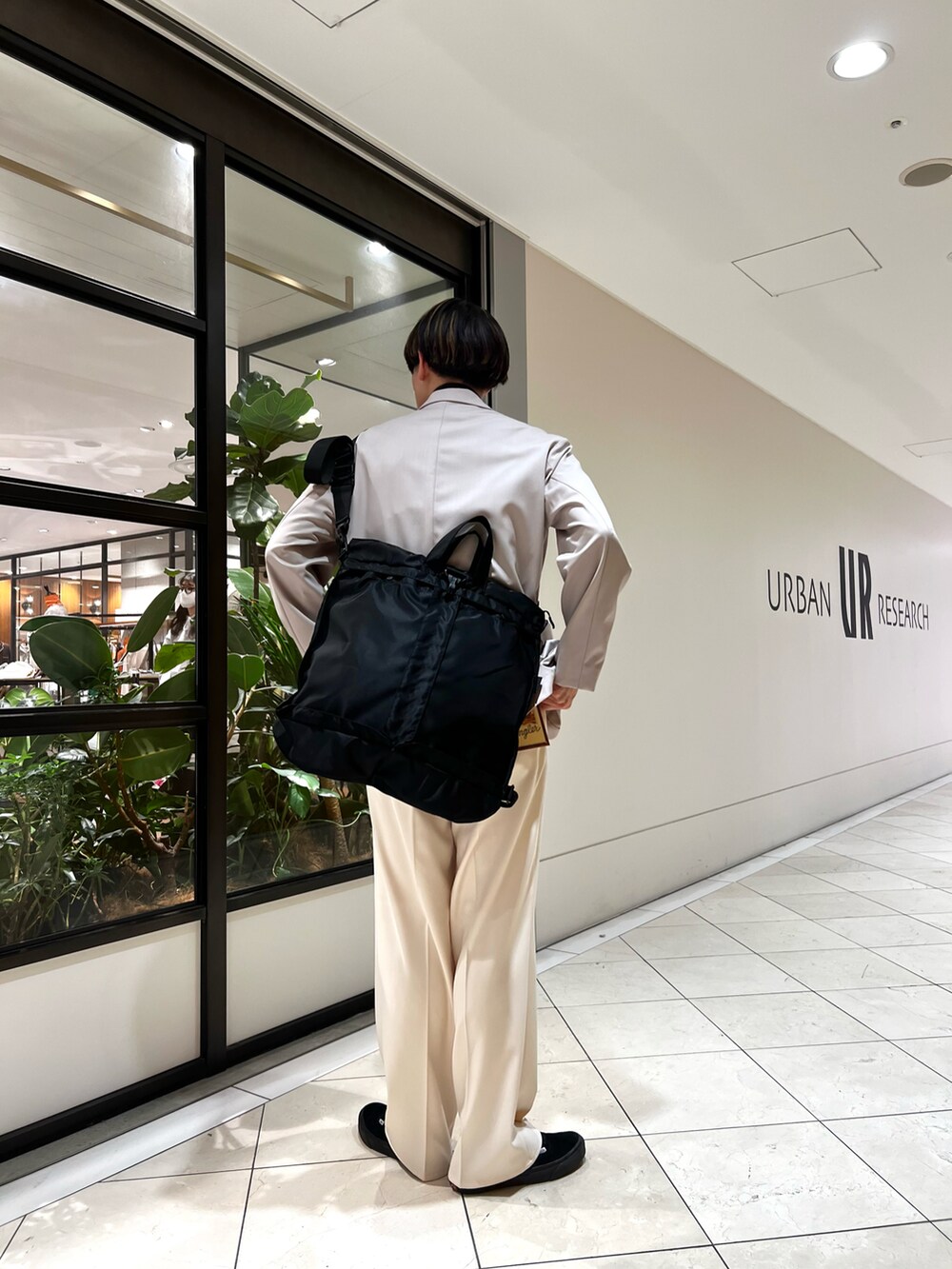 ブルー系のベスト、グレー系のその他アウター、ブラック系のトートバッグを着用したメンズの春コーディネートの2枚目の写真