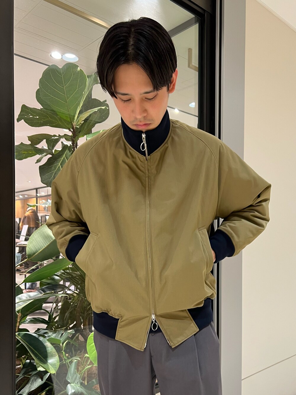 グリーン系のブルゾン、グレー系のスラックス、ブルー系のスウェットを着用したメンズの秋コーディネートの3枚目の写真