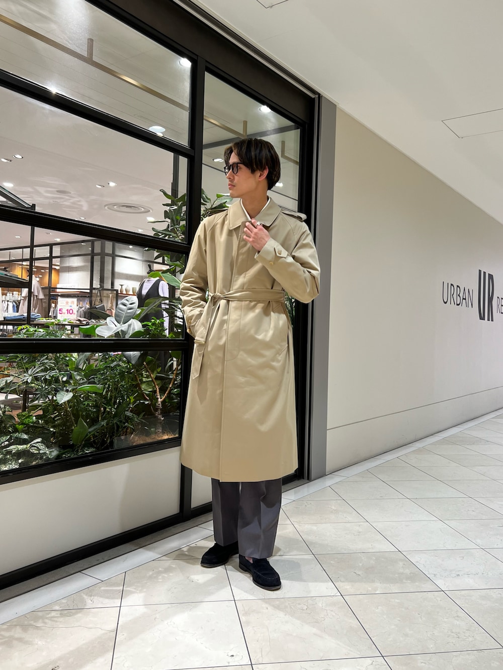 グレー系のスラックス、ベージュ系のトレンチコート、ホワイト系のスウェットを着用したメンズの春コーディネートの2枚目の写真