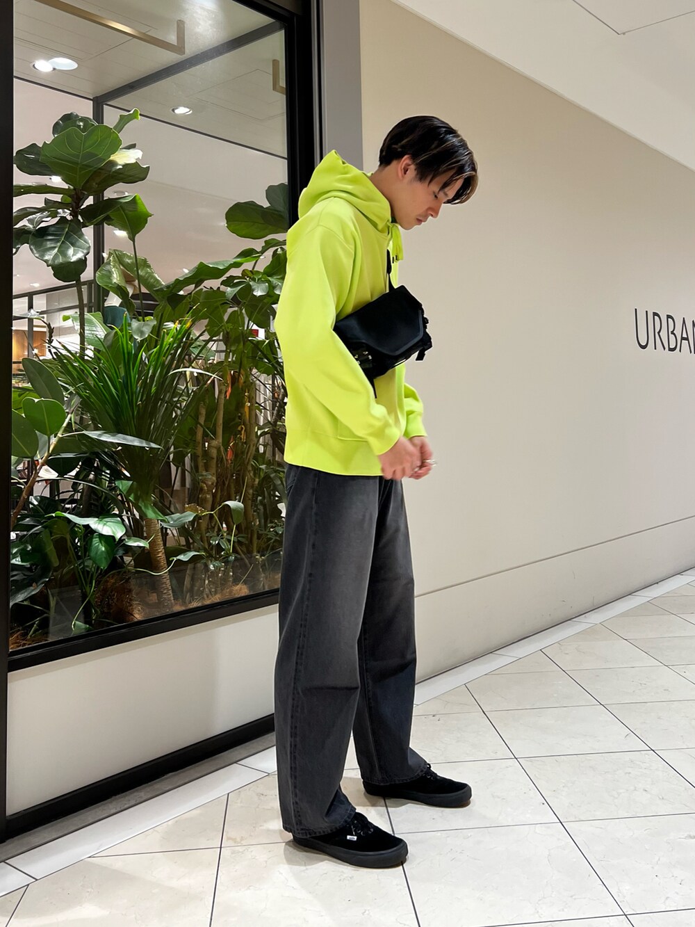 グリーン系のパーカー、ブラック系のショルダーバッグ、ブラック系のデニムパンツを着用したメンズの冬コーディネートの3枚目の写真