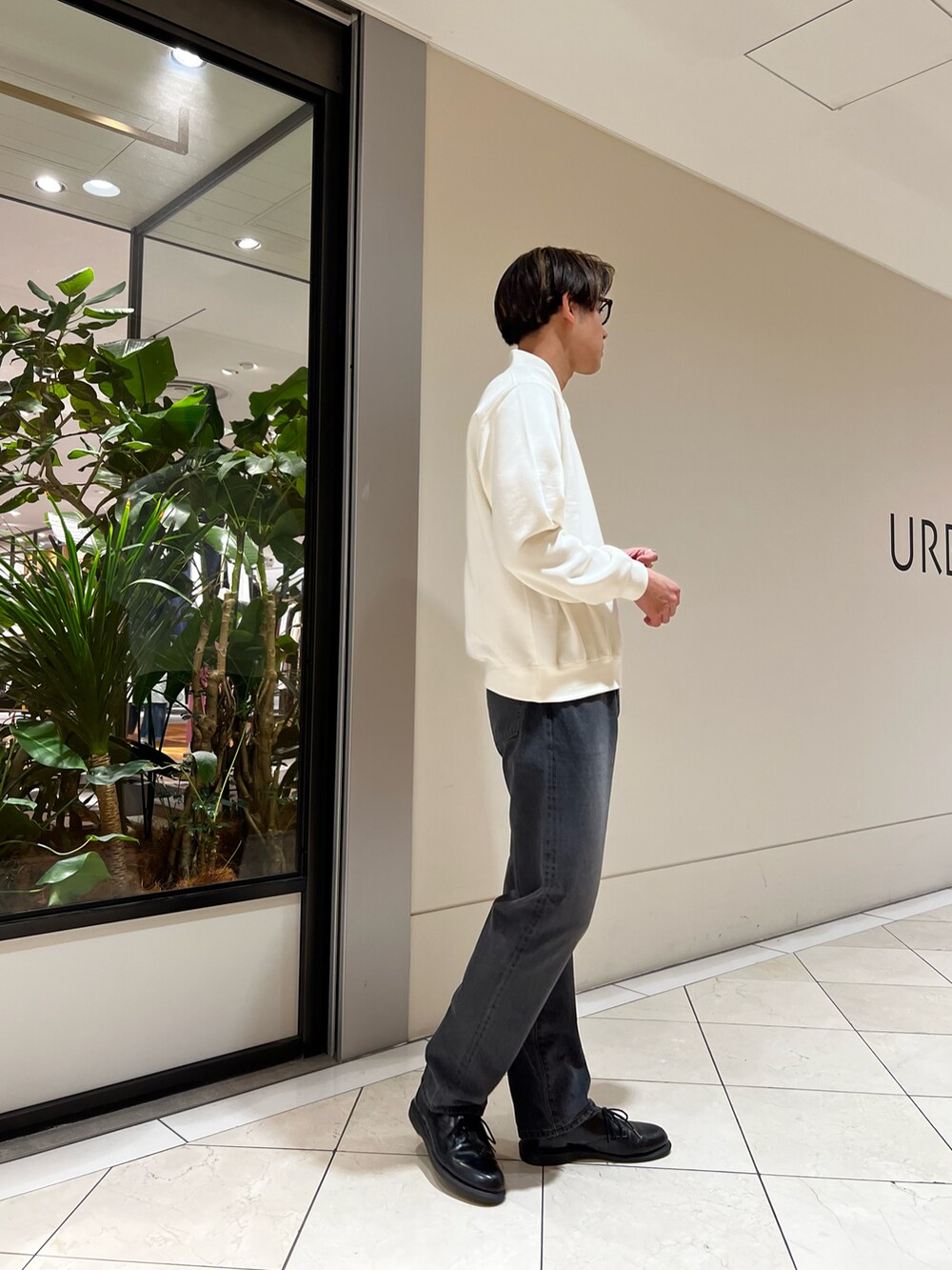 ホワイト系のスウェット、ブラック系のデニムパンツ、レッド系のメガネを着用したメンズの春コーディネートの2枚目の写真