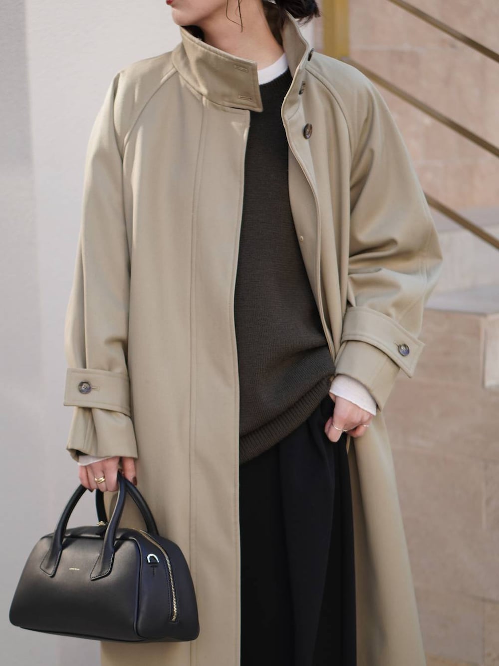 ブラック系のその他パンツ、ベージュ系のトレンチコート、ホワイト系のニット/セーターを着用したレディースの秋コーディネートの4枚目の写真