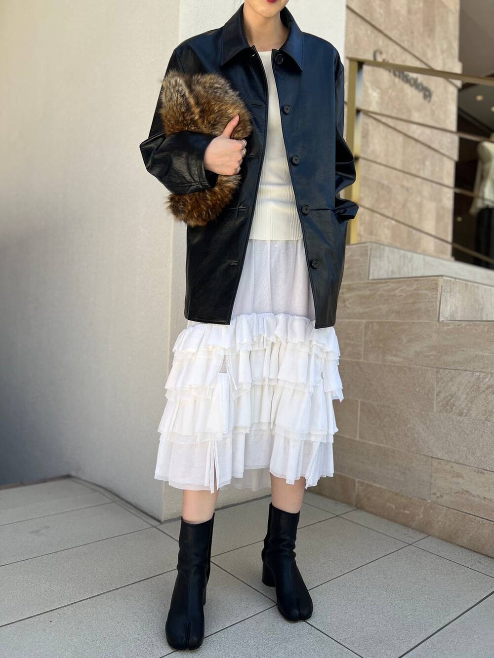 ホワイト系のタンクトップ、ホワイト系のスカート、ブラック系のブルゾンを着用したレディースの夏コーディネートの7枚目の写真