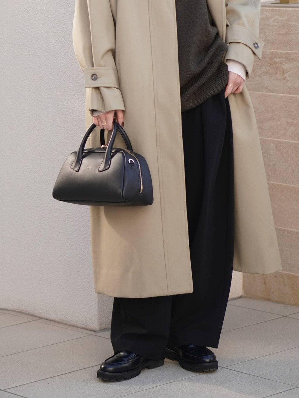 ブラック系のその他パンツ、ベージュ系のトレンチコート、ホワイト系のニット/セーターを着用したレディースの秋コーディネートの5枚目の写真