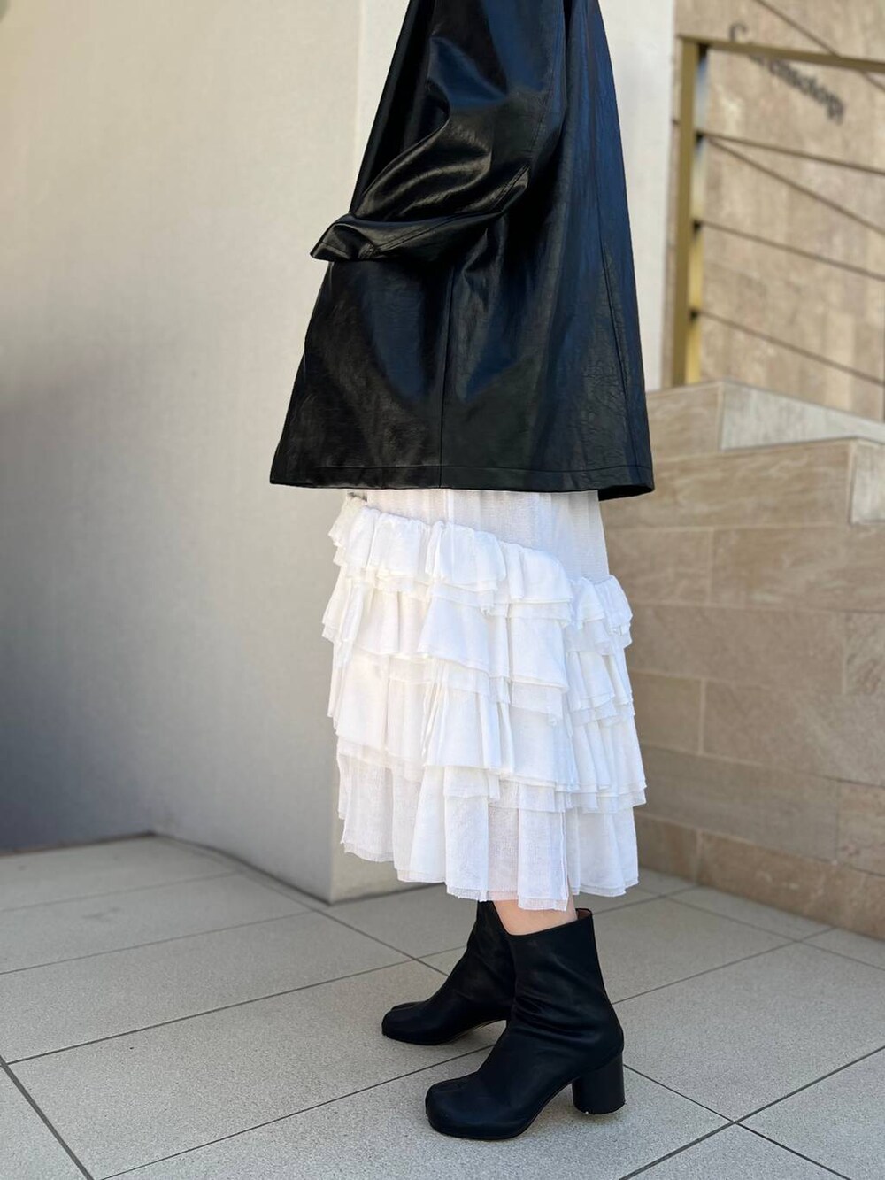 ホワイト系のタンクトップ、ホワイト系のスカート、ブラック系のブルゾンを着用したレディースの夏コーディネートの8枚目の写真